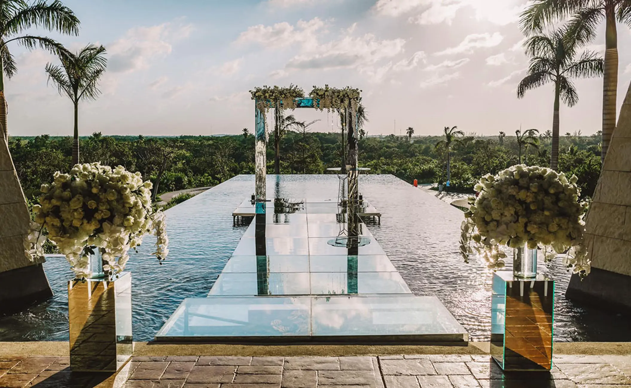 Over-the-water wedding ceremony aisle and floral arch at Atelier Playa Mujeres, Cancun