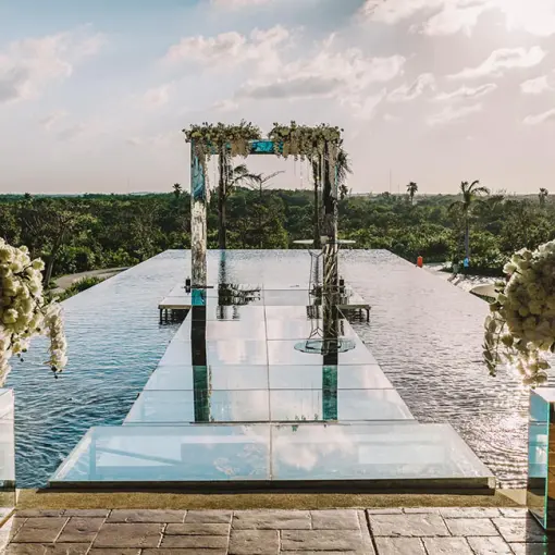 Over-the-water wedding ceremony aisle and floral arch at Atelier Playa Mujeres, Cancun