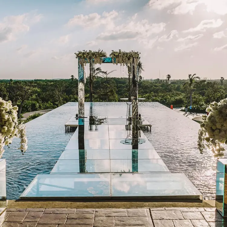Over-the-water wedding ceremony aisle and floral arch at Atelier Playa Mujeres, Cancun
