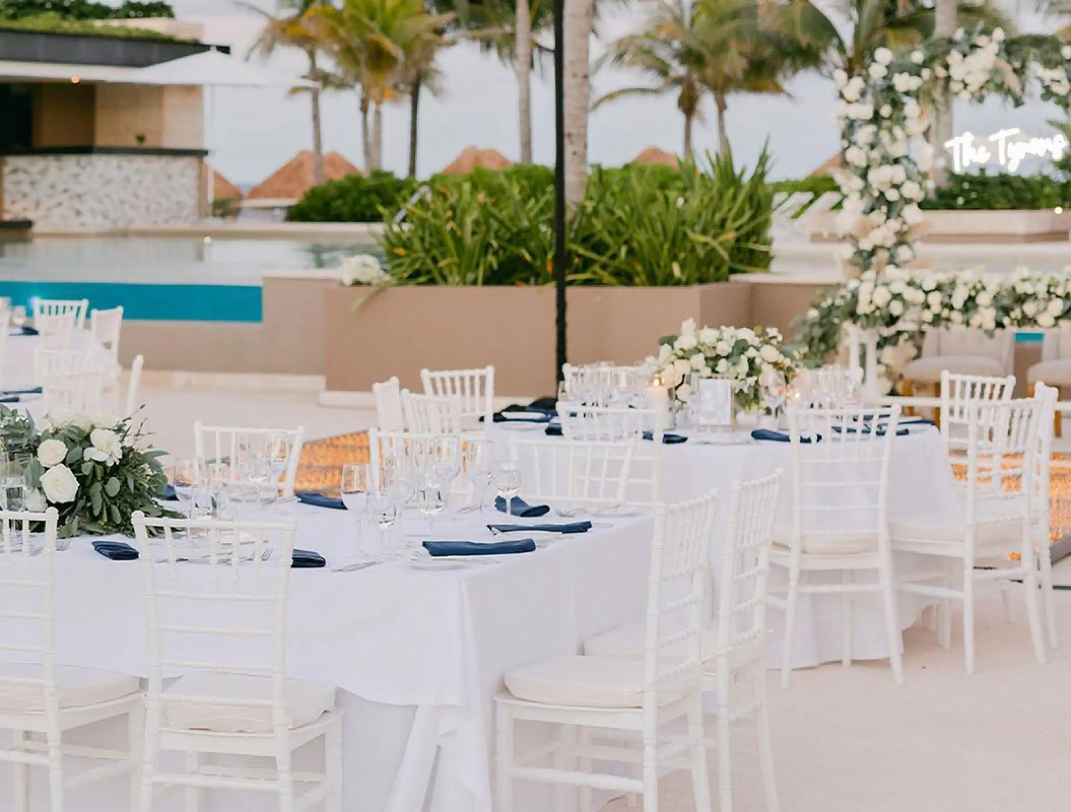 Terrace wedding reception with white floral centerpieces and navy napkins at Atelier Playa Mujeres, Cancun
