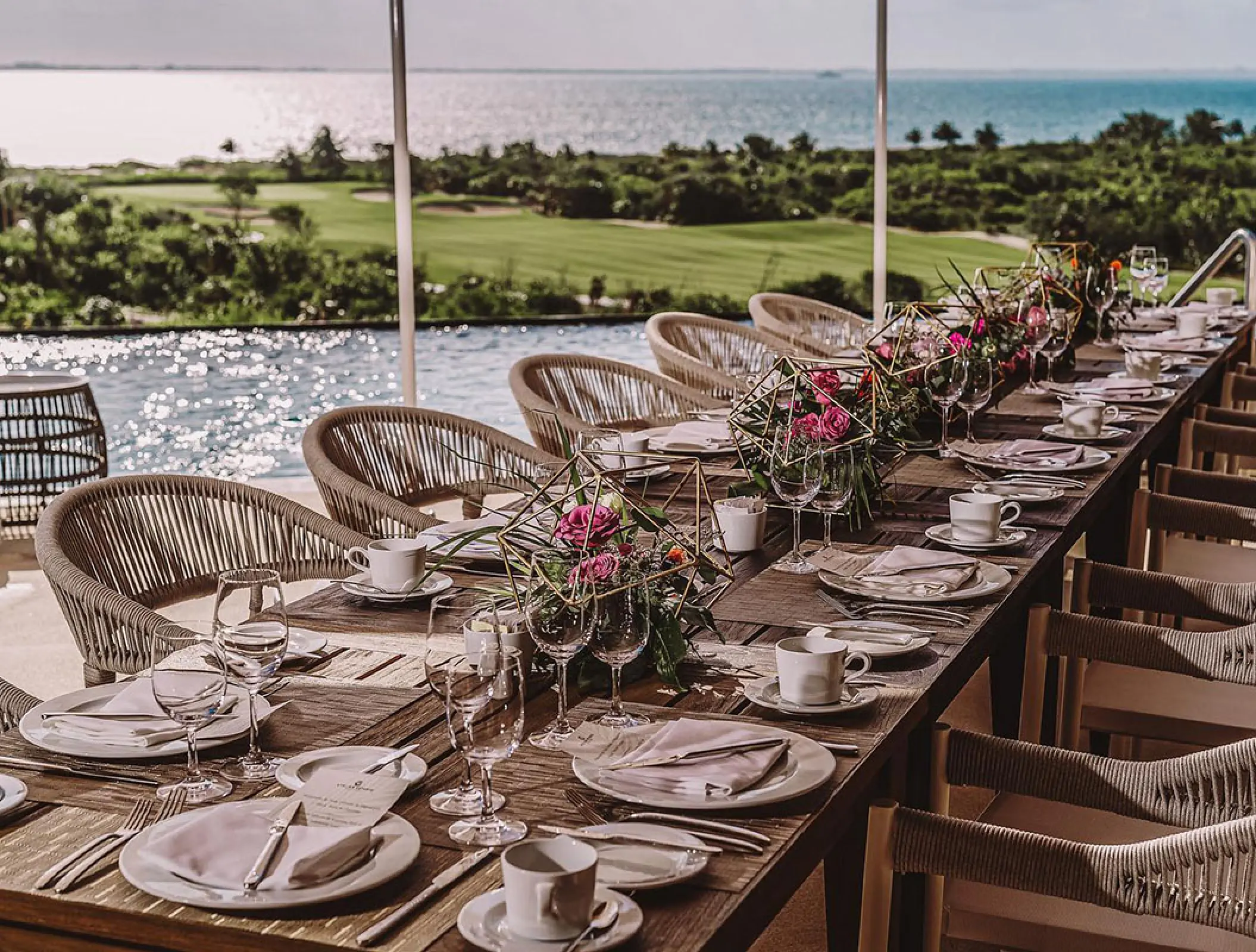Long wedding reception table overlooking the pool and ocean at Atelier Playa Mujeres, Cancun