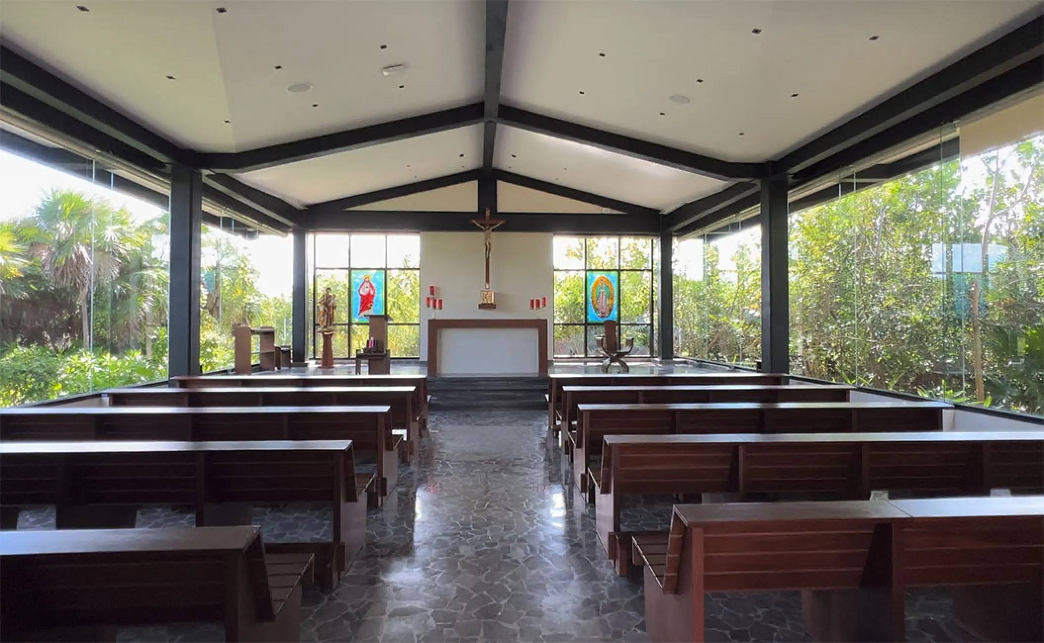 Indoor wedding chapel with wooden pews and glass walls at Atelier Playa Mujeres, Cancun