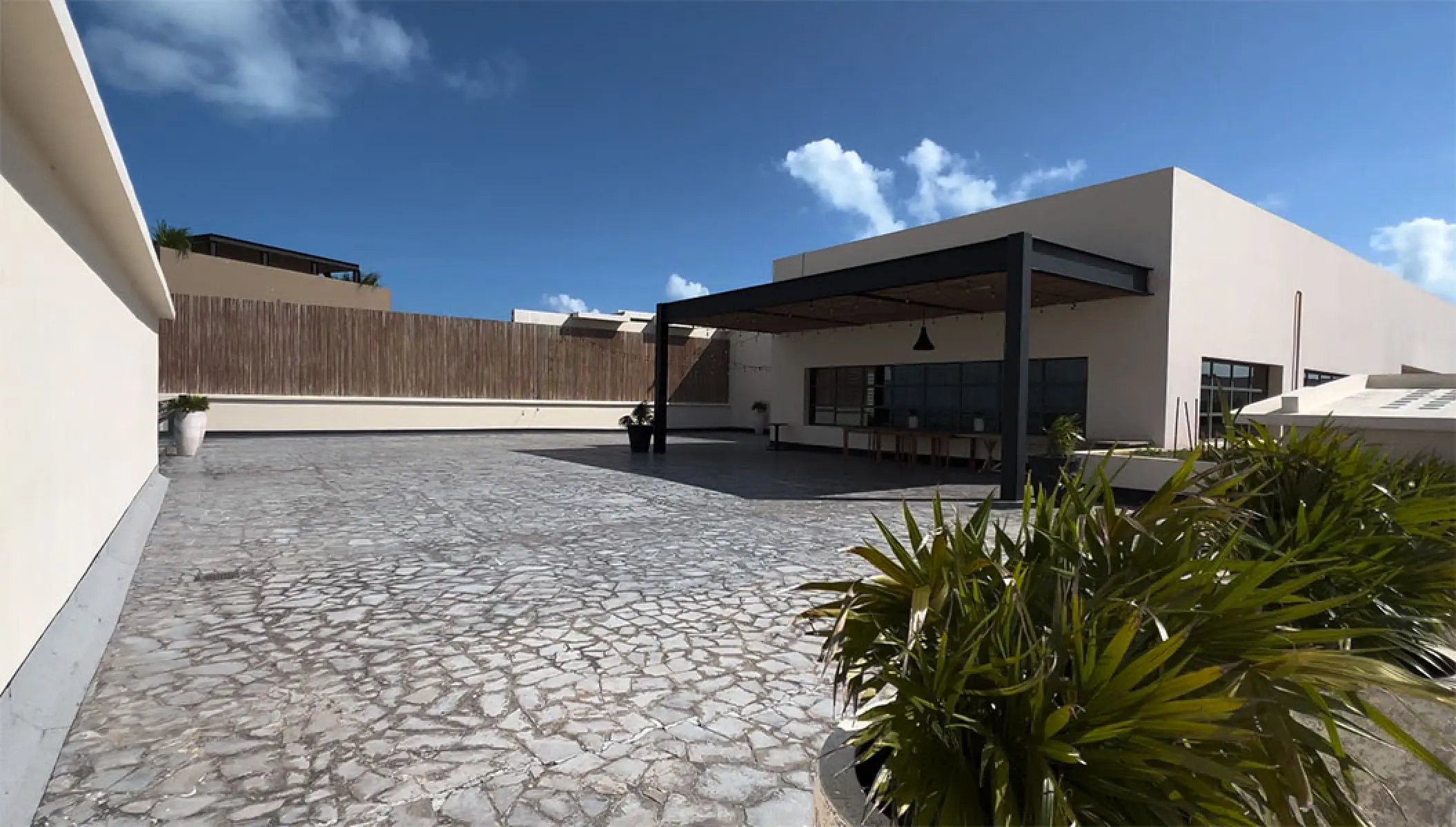 Los Abrazos Terrace wedding venue with stone flooring and modern pergola at Atelier Playa Mujeres, Cancun