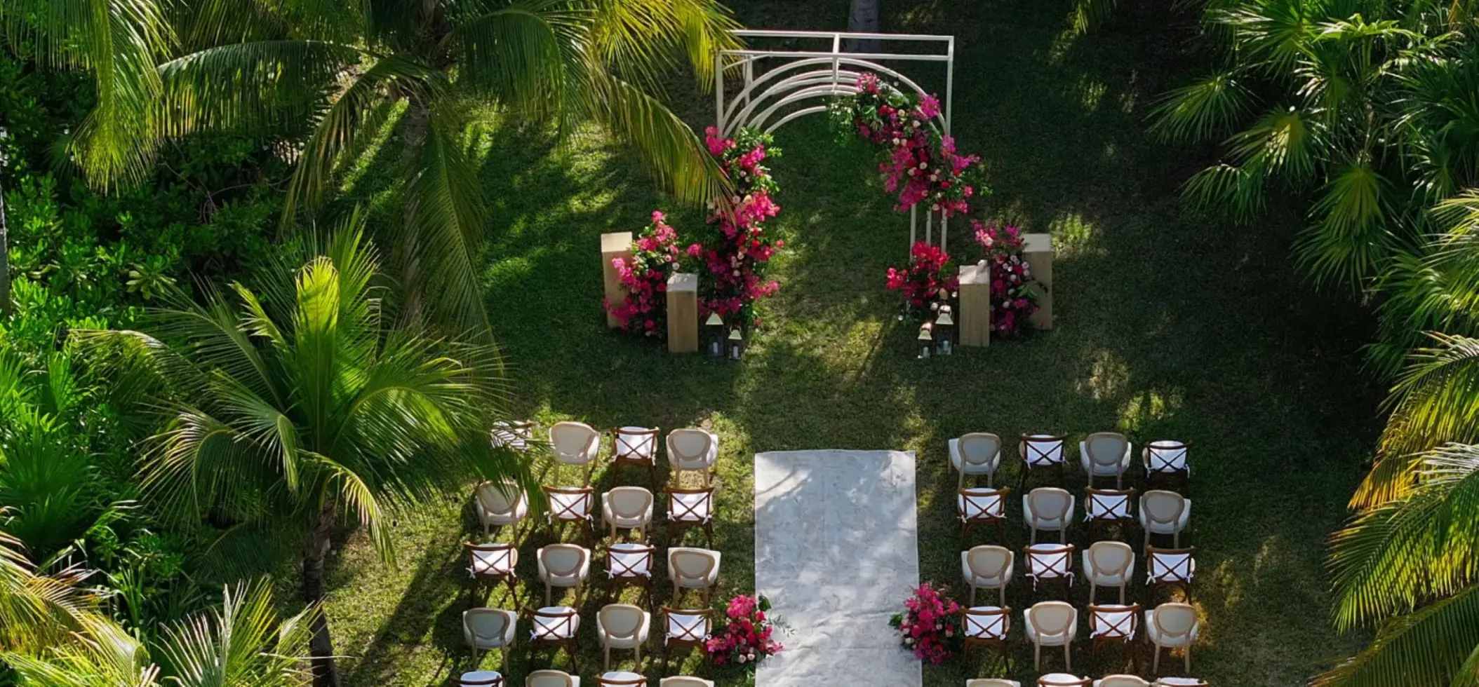 Garden wedding ceremony setup with pink flowers and a white arch at Atelier Playa Mujeres, Cancun