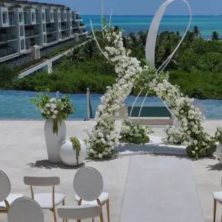 Rooftop wedding ceremony setup with white floral arch at Atelier Playa Mujeres, Cancun