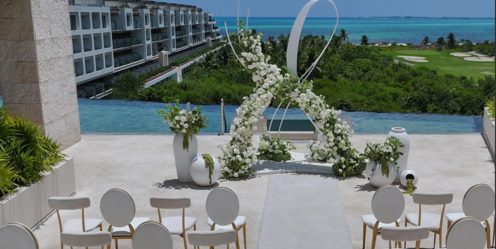 Rooftop wedding ceremony setup with white floral arch at Atelier Playa Mujeres, Cancun