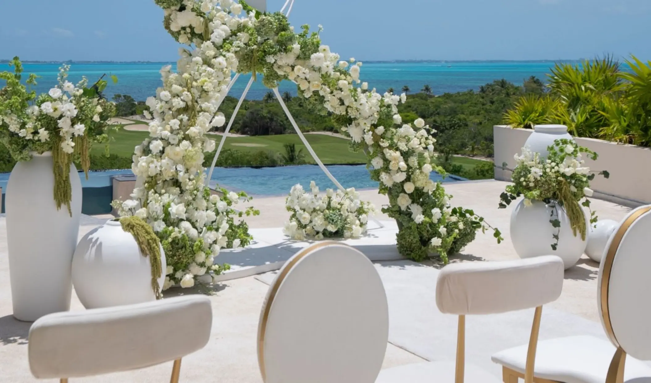 White floral arch at an outdoor wedding ceremony at Atelier Playa Mujeres, Cancun