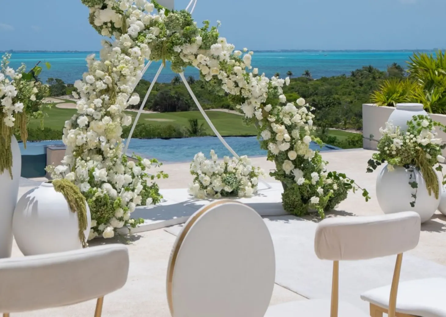 White floral arch at an outdoor wedding ceremony at Atelier Playa Mujeres, Cancun