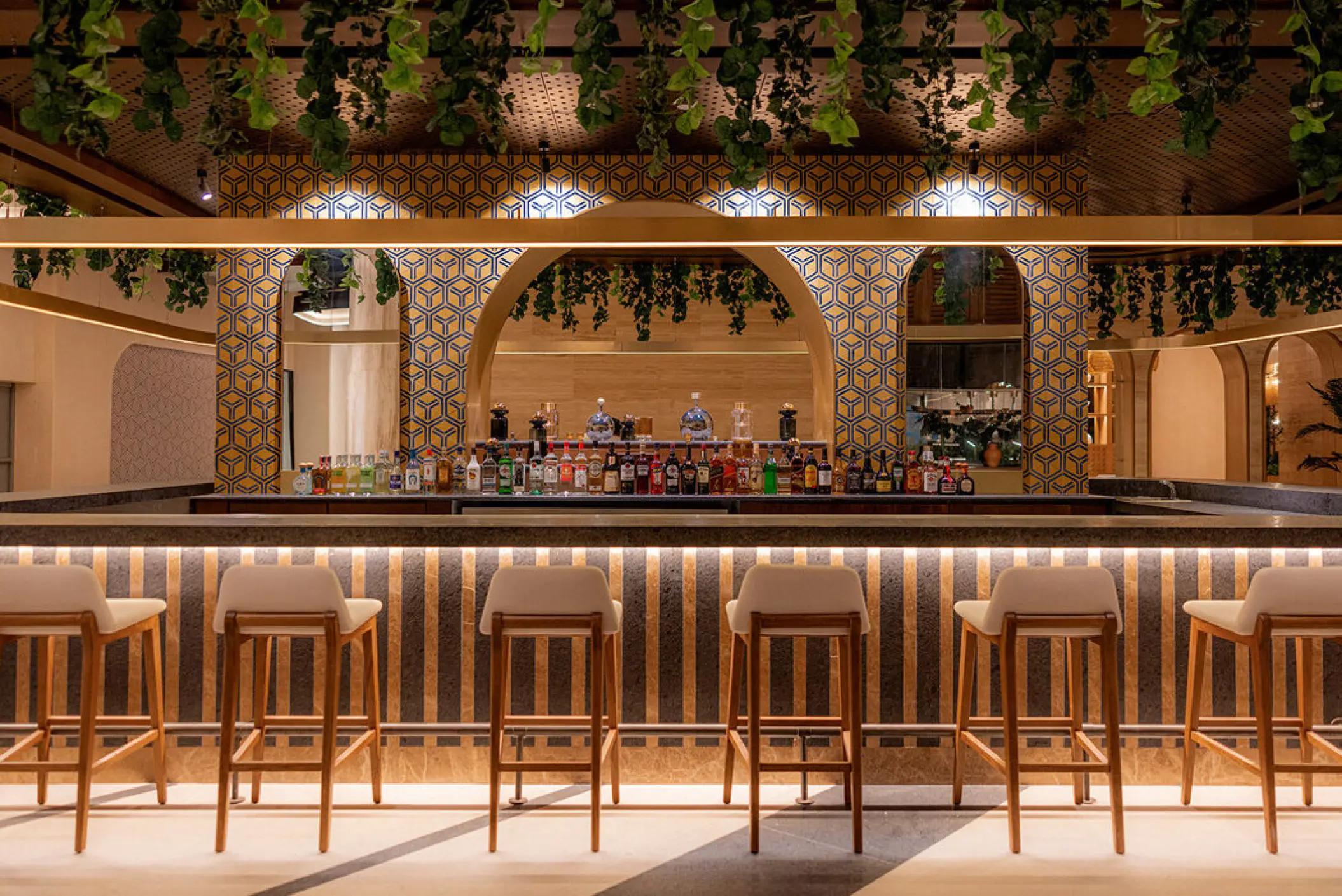 Modern cocktail bar with hanging greenery and striped counter at AVA Resort Cancun