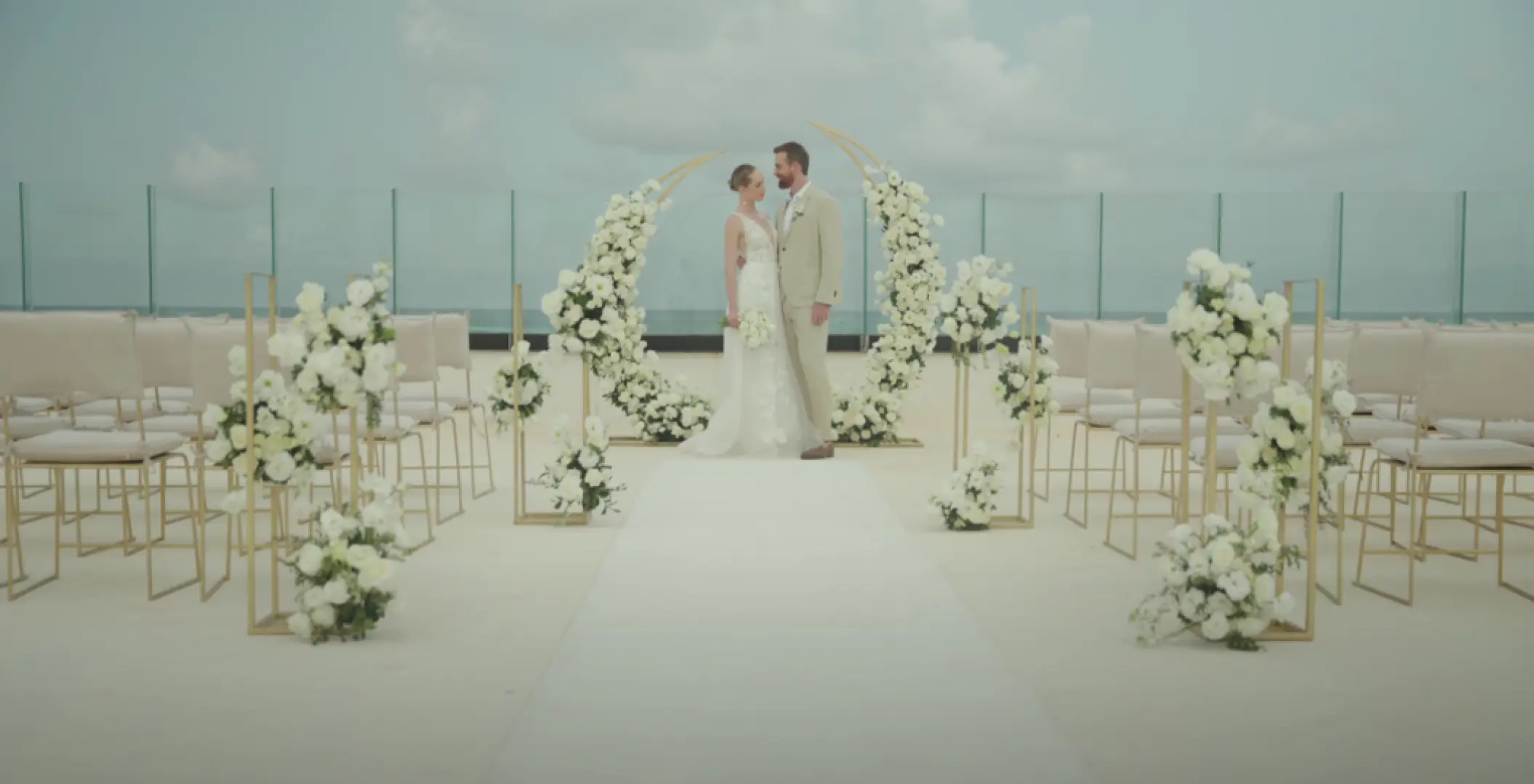 The bride and groom standing before a floral circular arch at a terrace wedding ceremony setup in AVA Resort Cancun