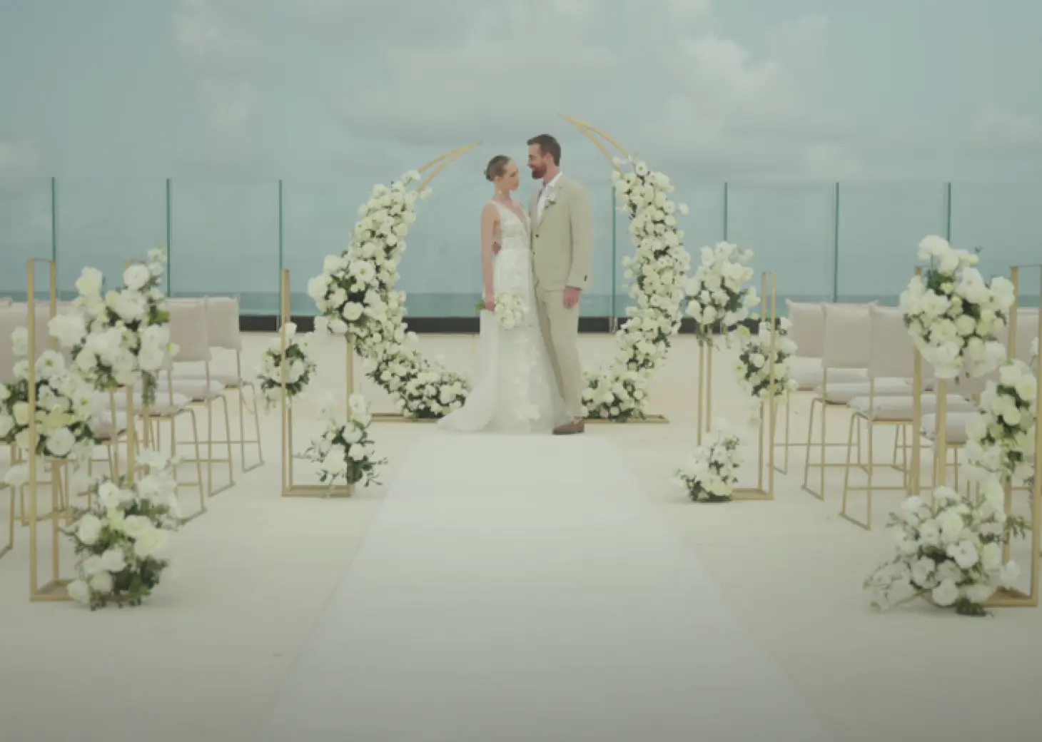 The bride and groom standing before a floral circular arch at a terrace wedding ceremony setup in AVA Resort Cancun