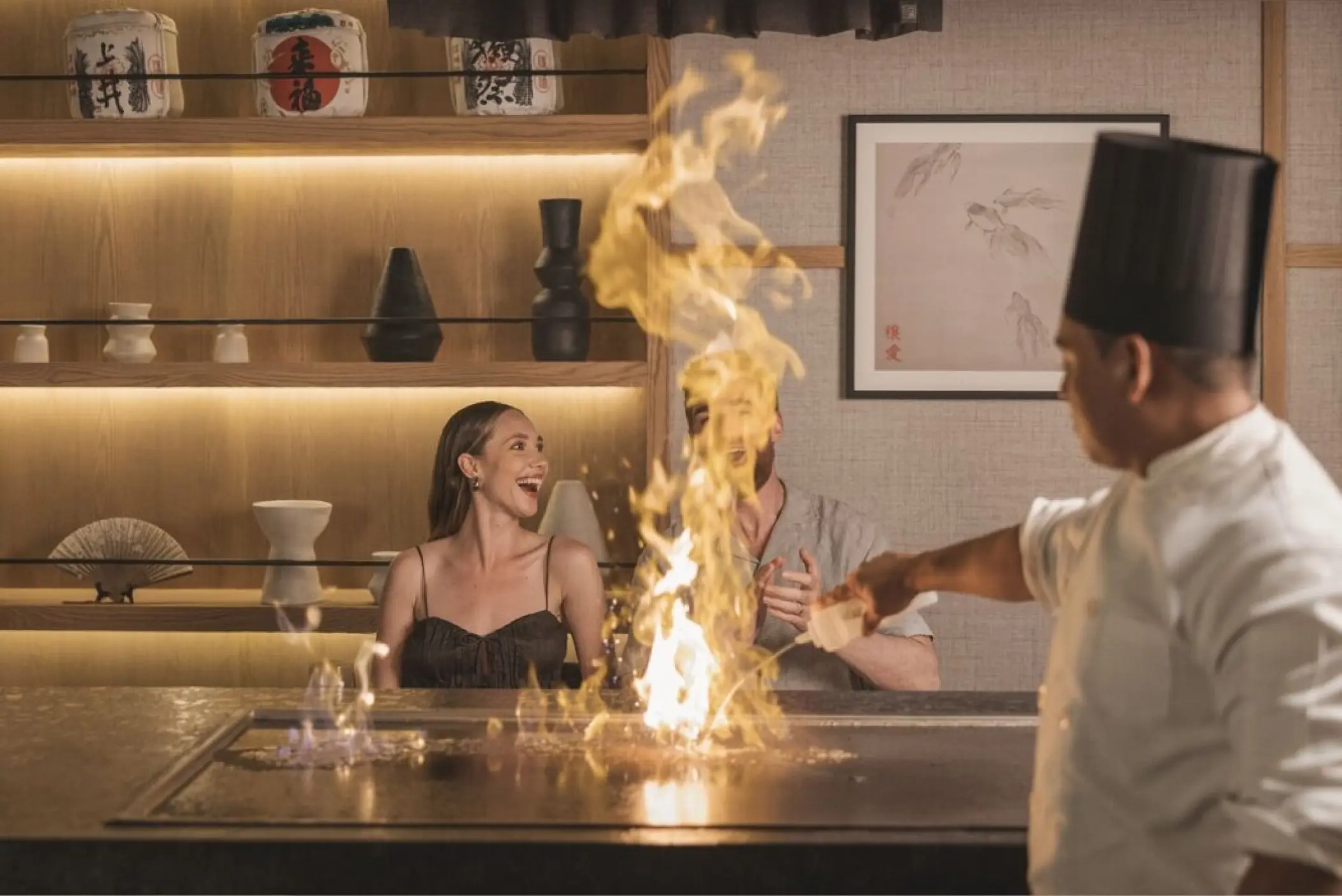 Chef performing a teppanyaki cooking show with flames for a couple at AVA Resort Cancun