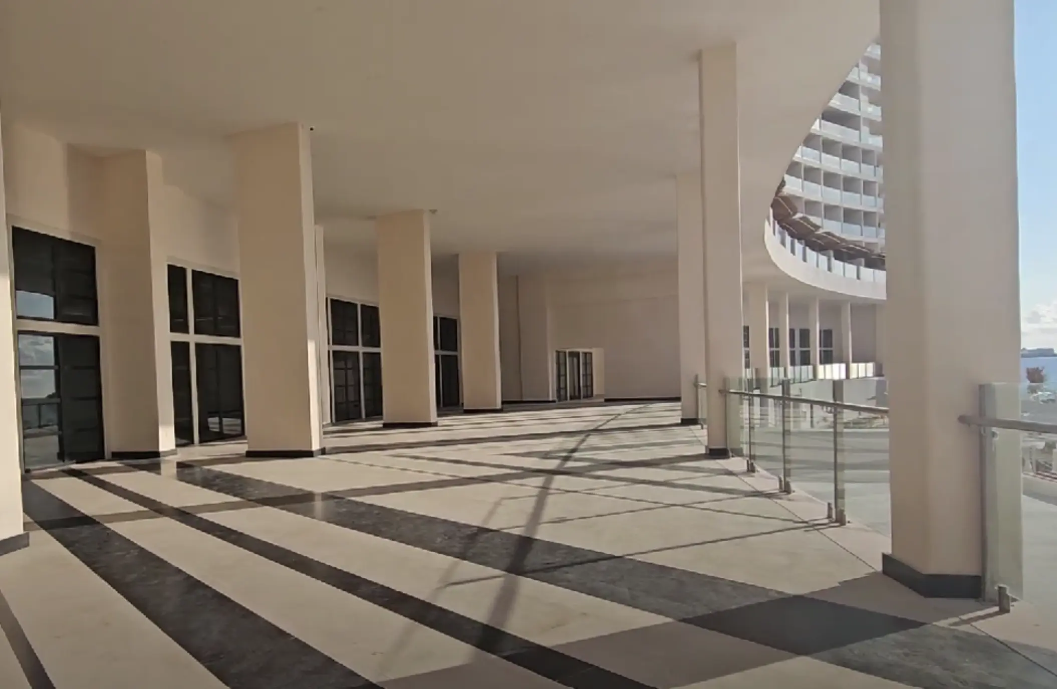 Modern panoramic terrace with glass railings and white pillars at AVA Resort Cancun