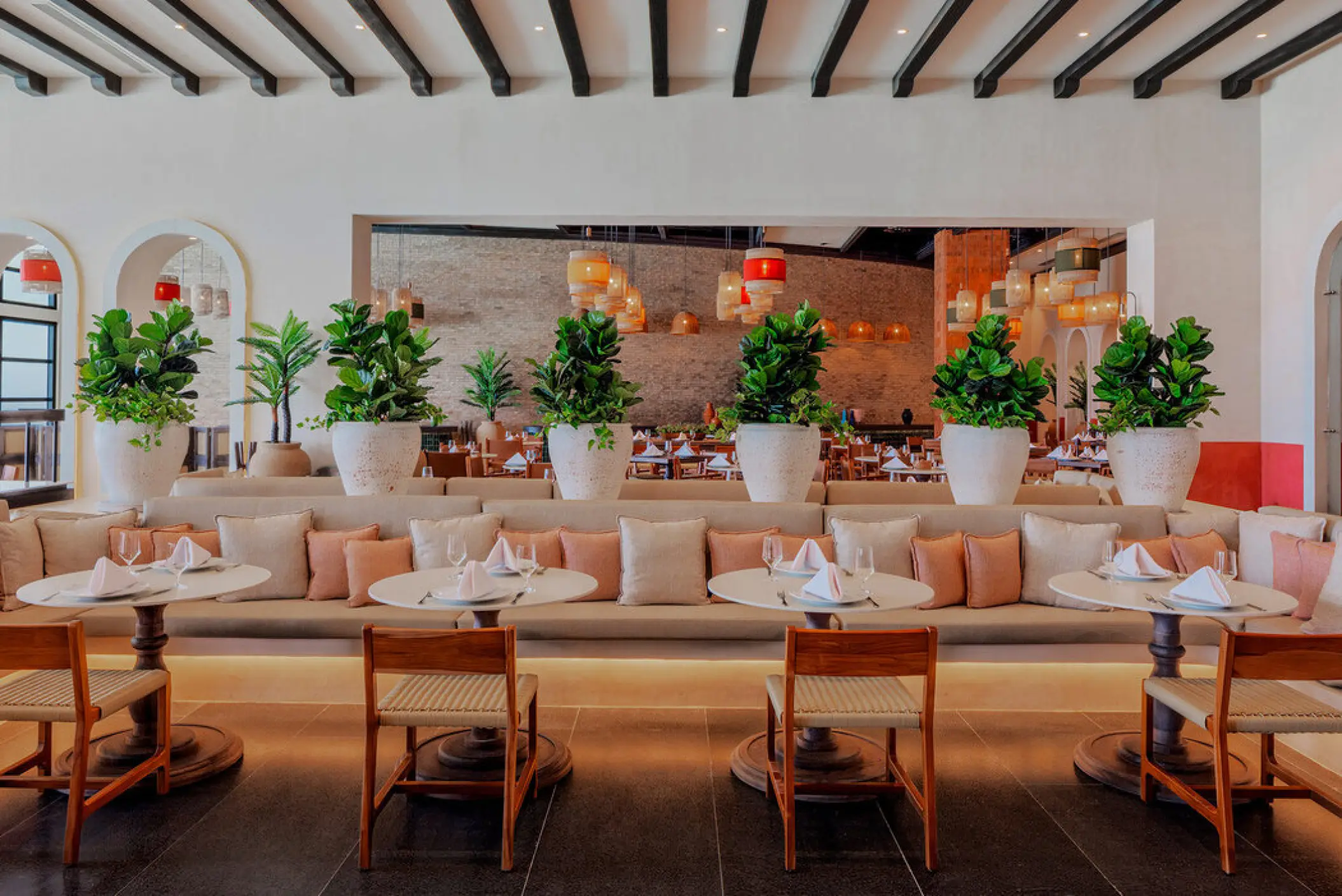 Modern restaurant dining area with banquet seating and potted plants at AVA Resort Cancun, Cancun