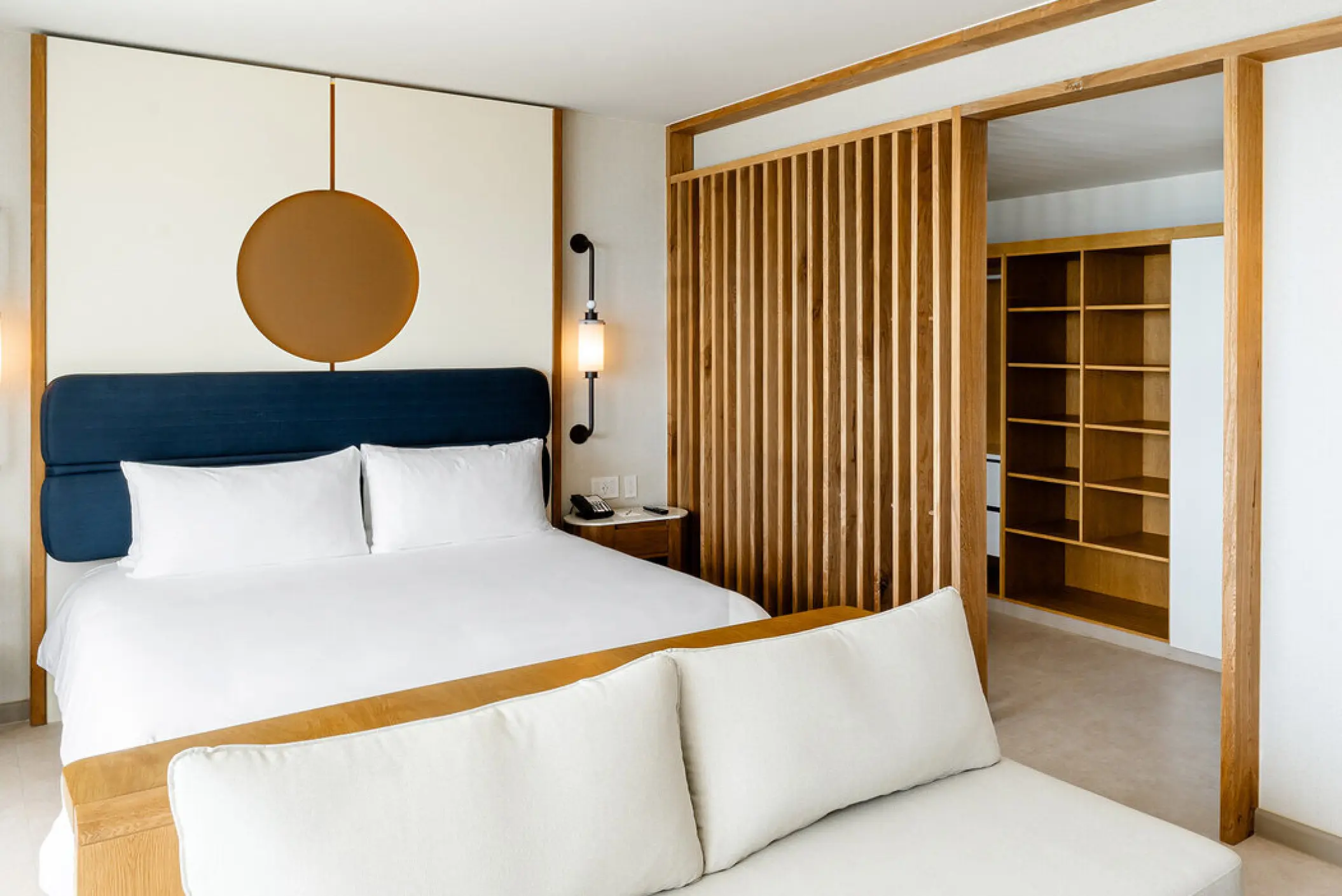 Modern suite with a king bed and wooden slat room divider at AVA Resort Cancun
