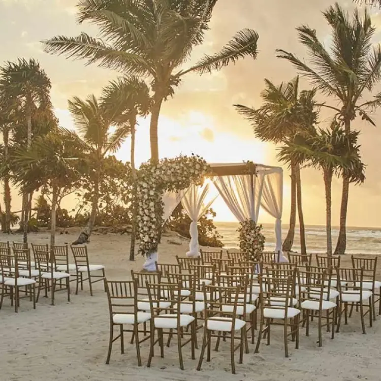 Beachfront wedding ceremony with white huppa and gold chairs at Bahia Principe Grand Coba, Tulum