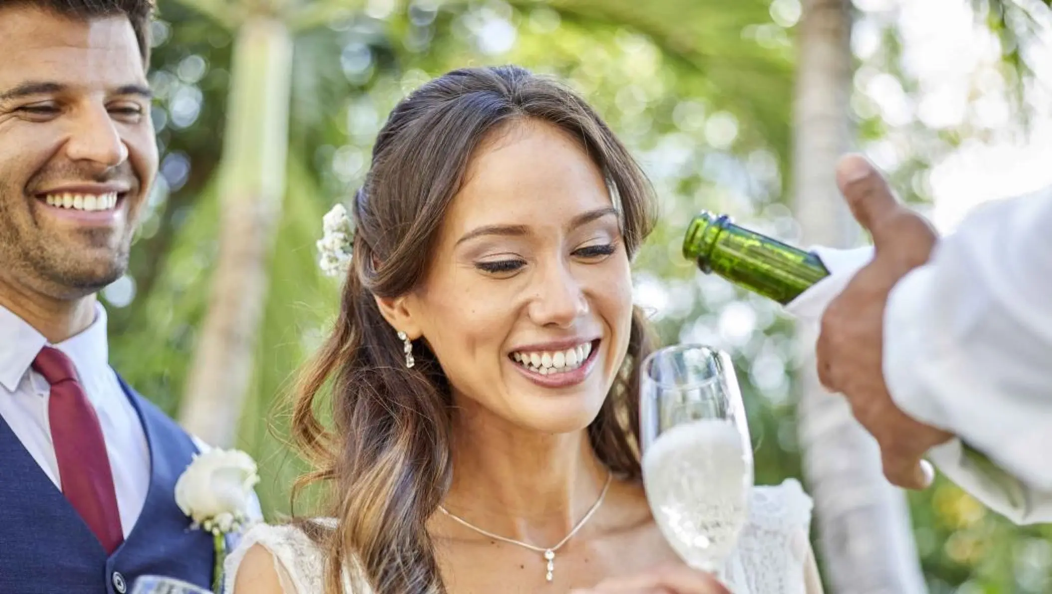 Smiling couple being served champagne during their wedding at Bahia Principe Grand Coba, Tulum