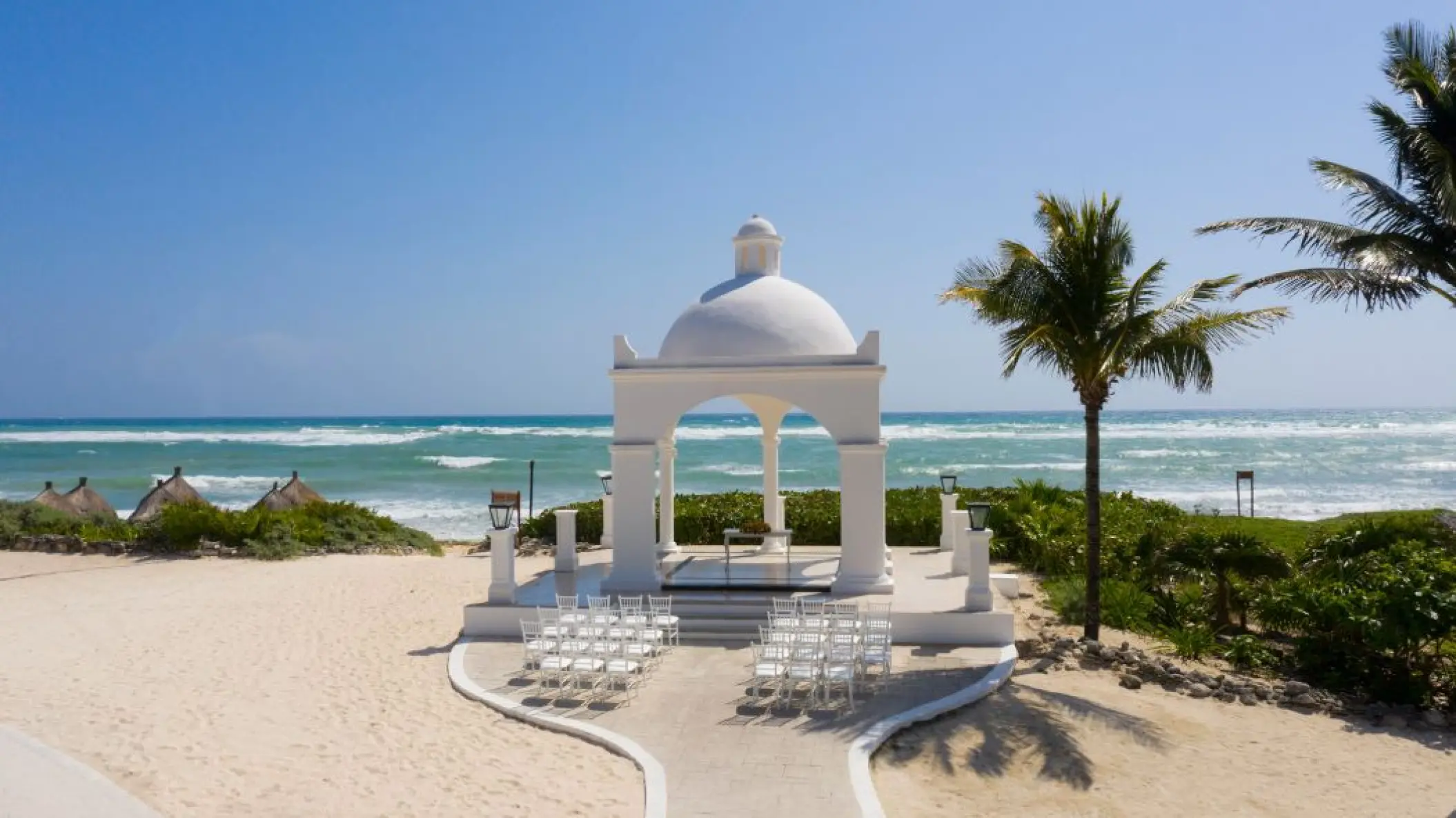 Oceanfront wedding ceremony gazebo with white chairs at Bahia Principe Grand Coba, Tulum