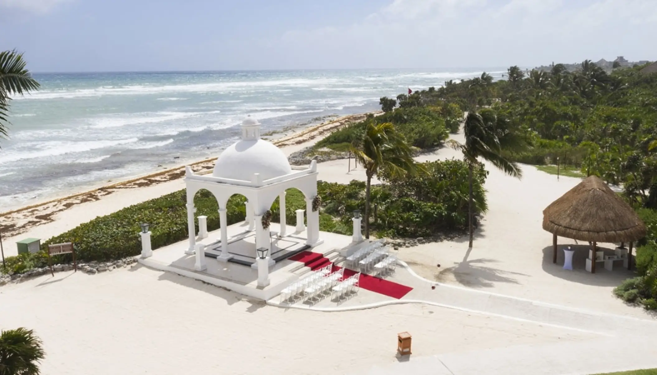 White beachfront wedding gazebo with a red aisle runner at Bahia Principe Grand Coba, Tulum