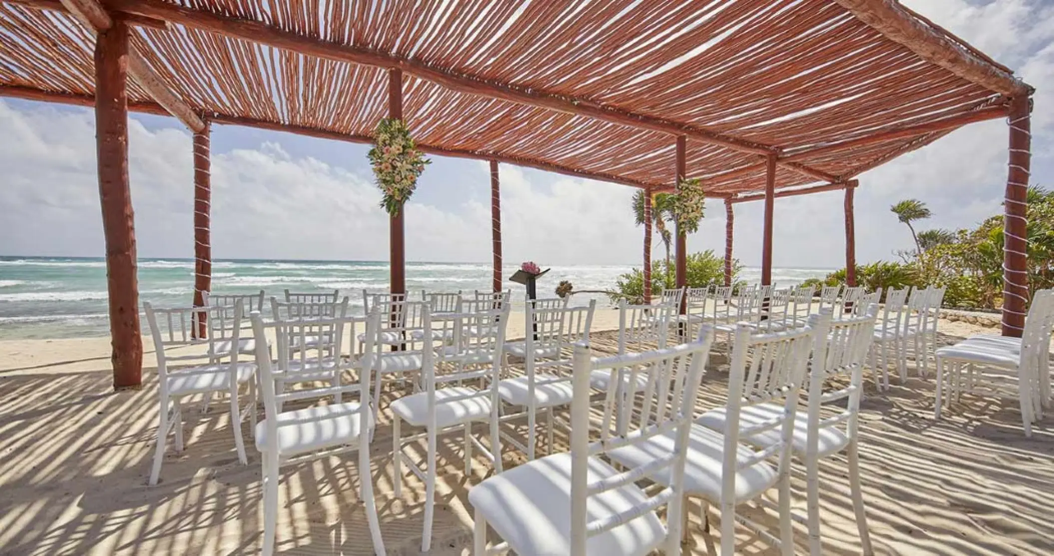 Beachfront wedding ceremony setup under a wooden pergola at Bahia Principe Grand Coba, Tulum