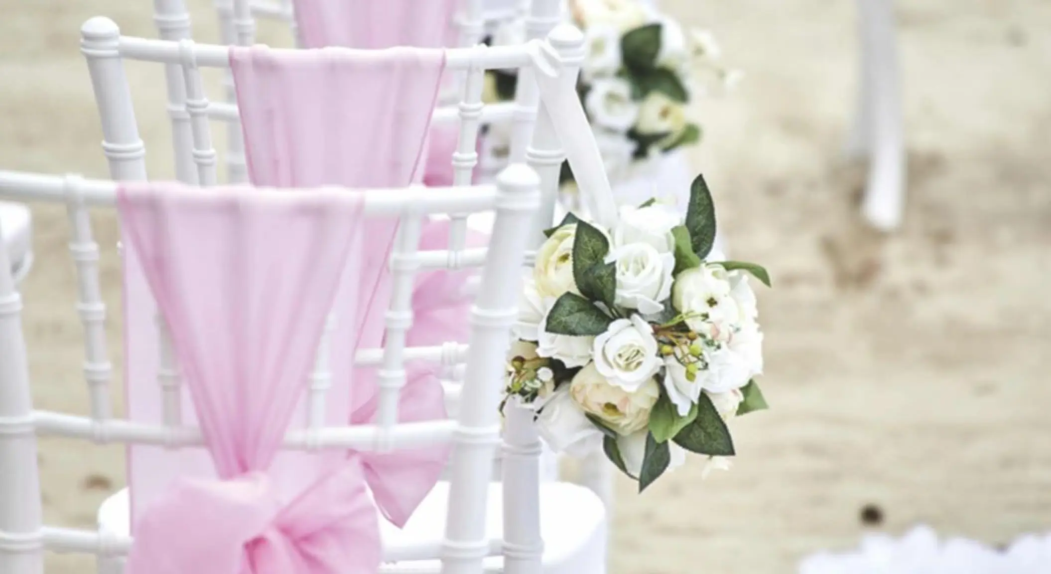 White chiavari chairs with pink sashes and white floral bouquets for a wedding at Bahia Principe Grand Coba, Tulum