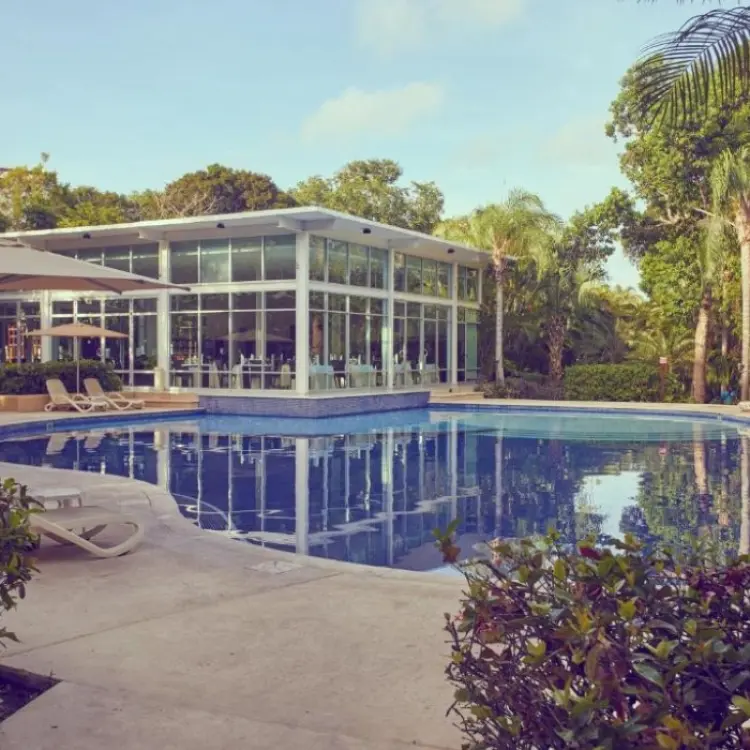 Curved outdoor swimming pool and glass pavilion at Bahia Principe Sian Ka’an, Tulum