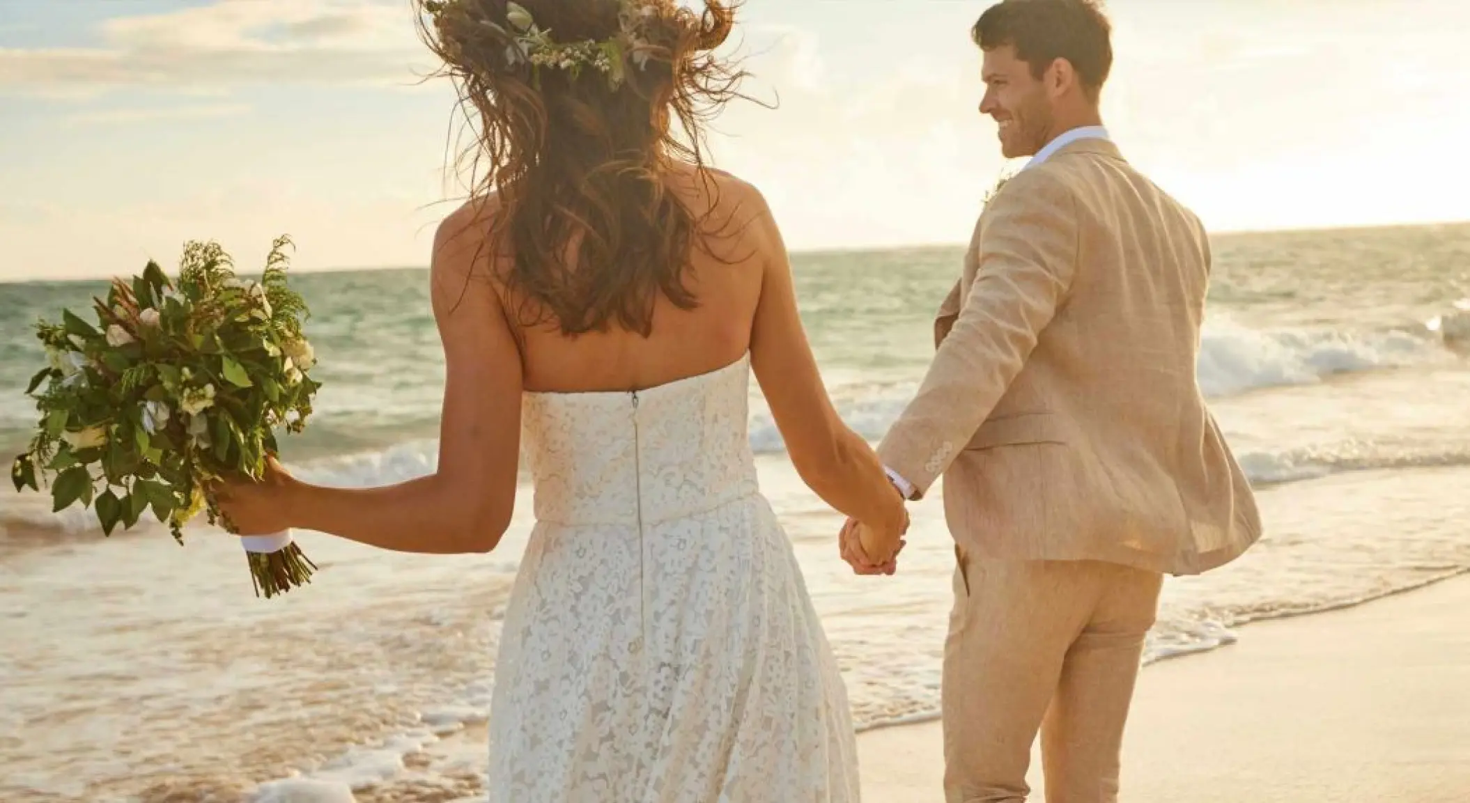 The bride and groom holding hands and walking on the beach at Bahia Principe Luxury Sian Ka’an, Tulum