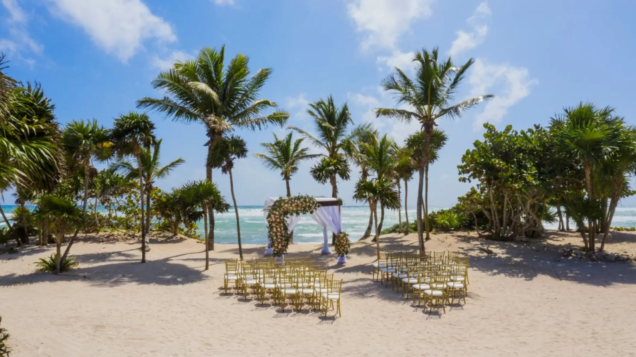Beachfront wedding ceremony with a floral huppa at Bahia Principe Luxury Sian Ka’an, Tulum
