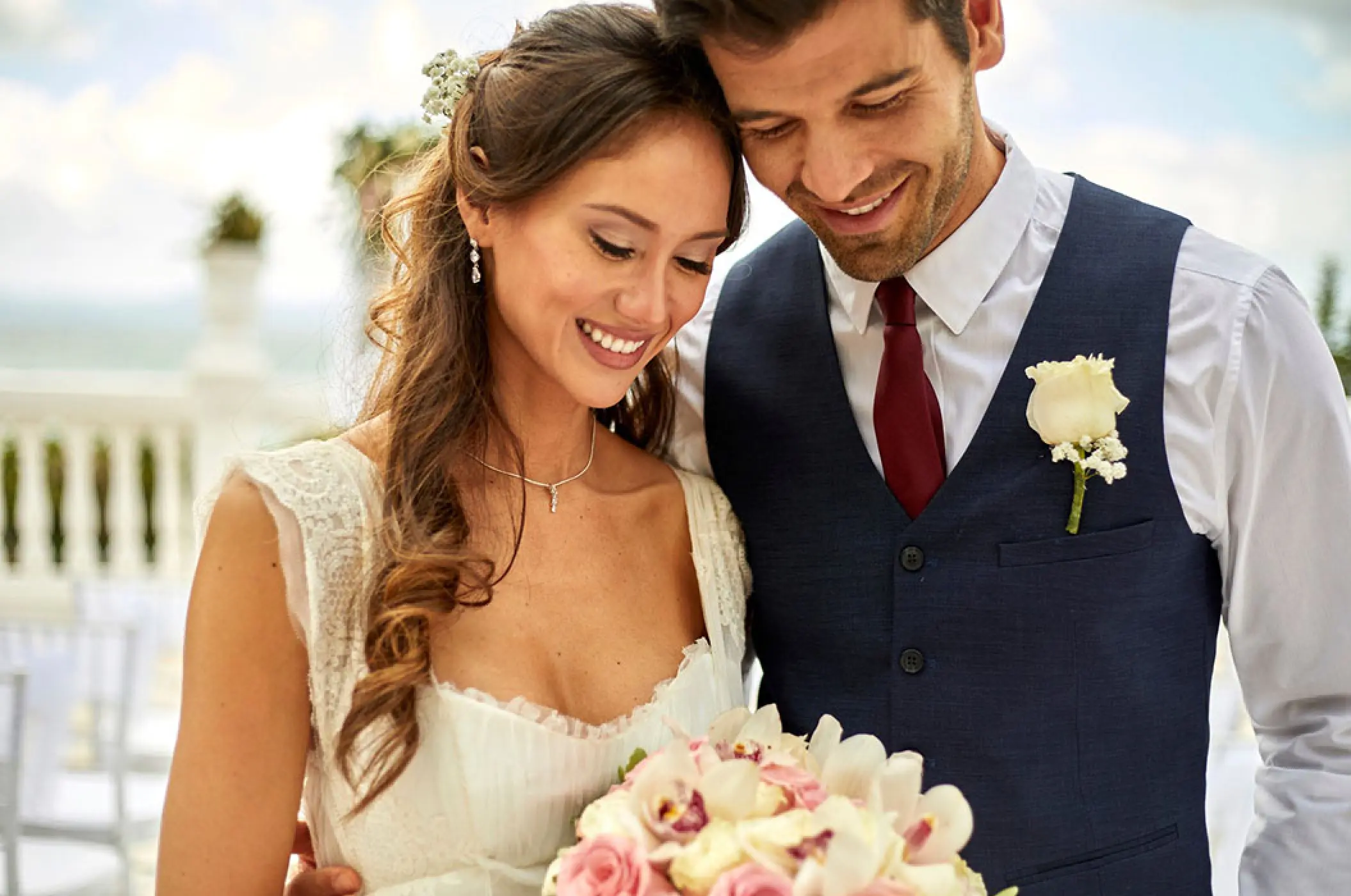 Bride and groom smiling at a bouquet during their wedding at Bahia Principe Luxury Akumal, Tulum