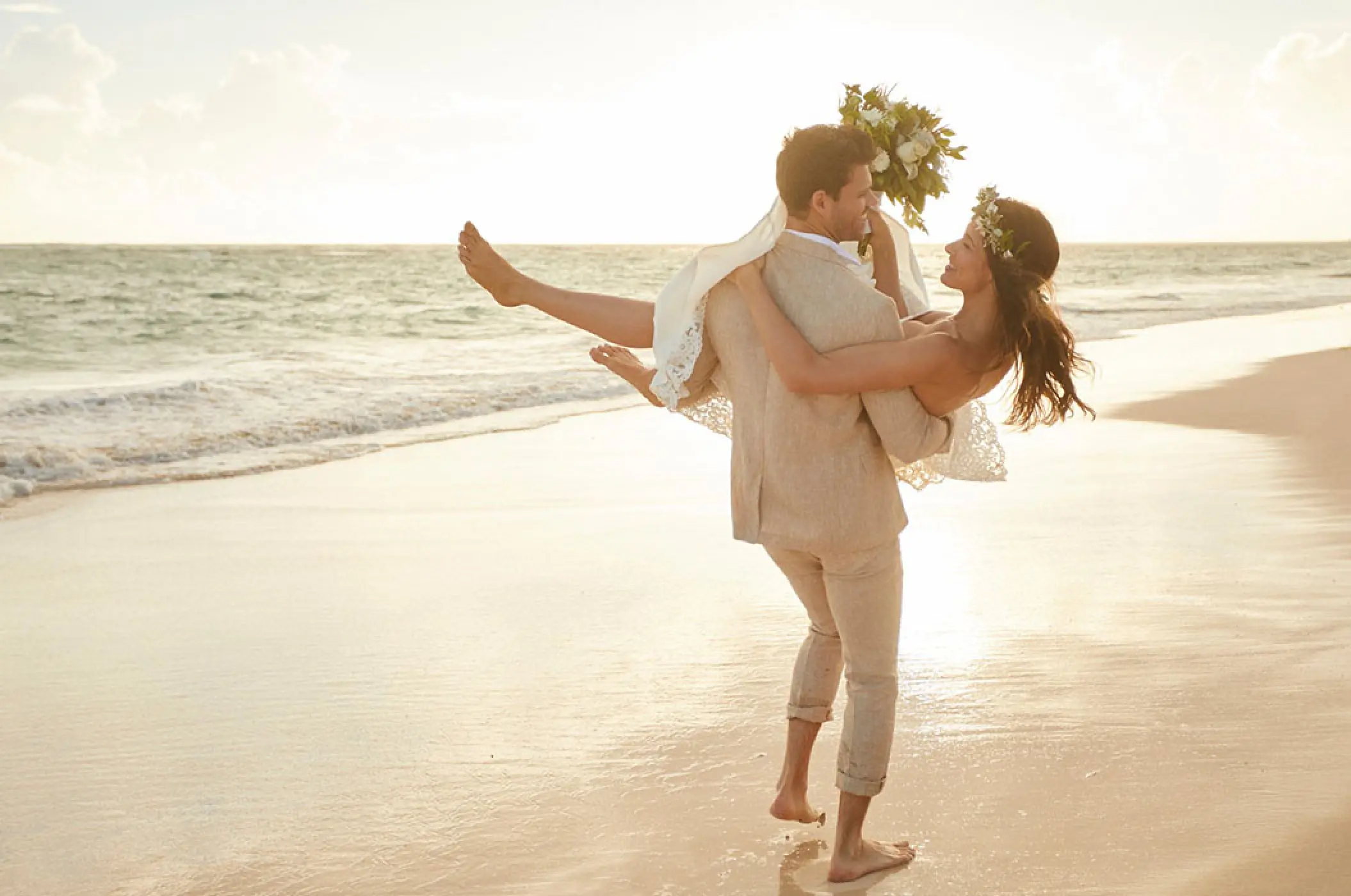 Groom carrying bride on the beach at Bahia Principe Luxury Akumal, Tulum