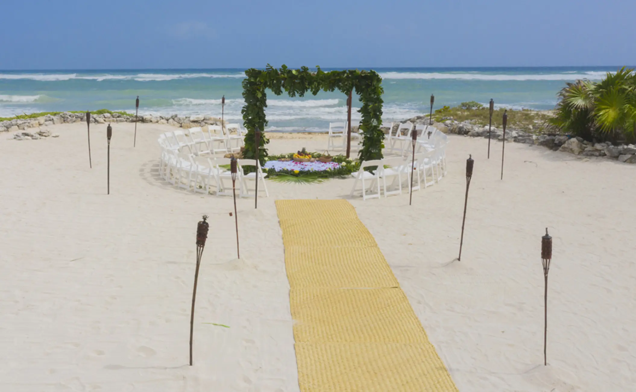 Beachfront wedding ceremony with greenery arch and circular seating at Bahia Principe Luxury Akumal, Tulum