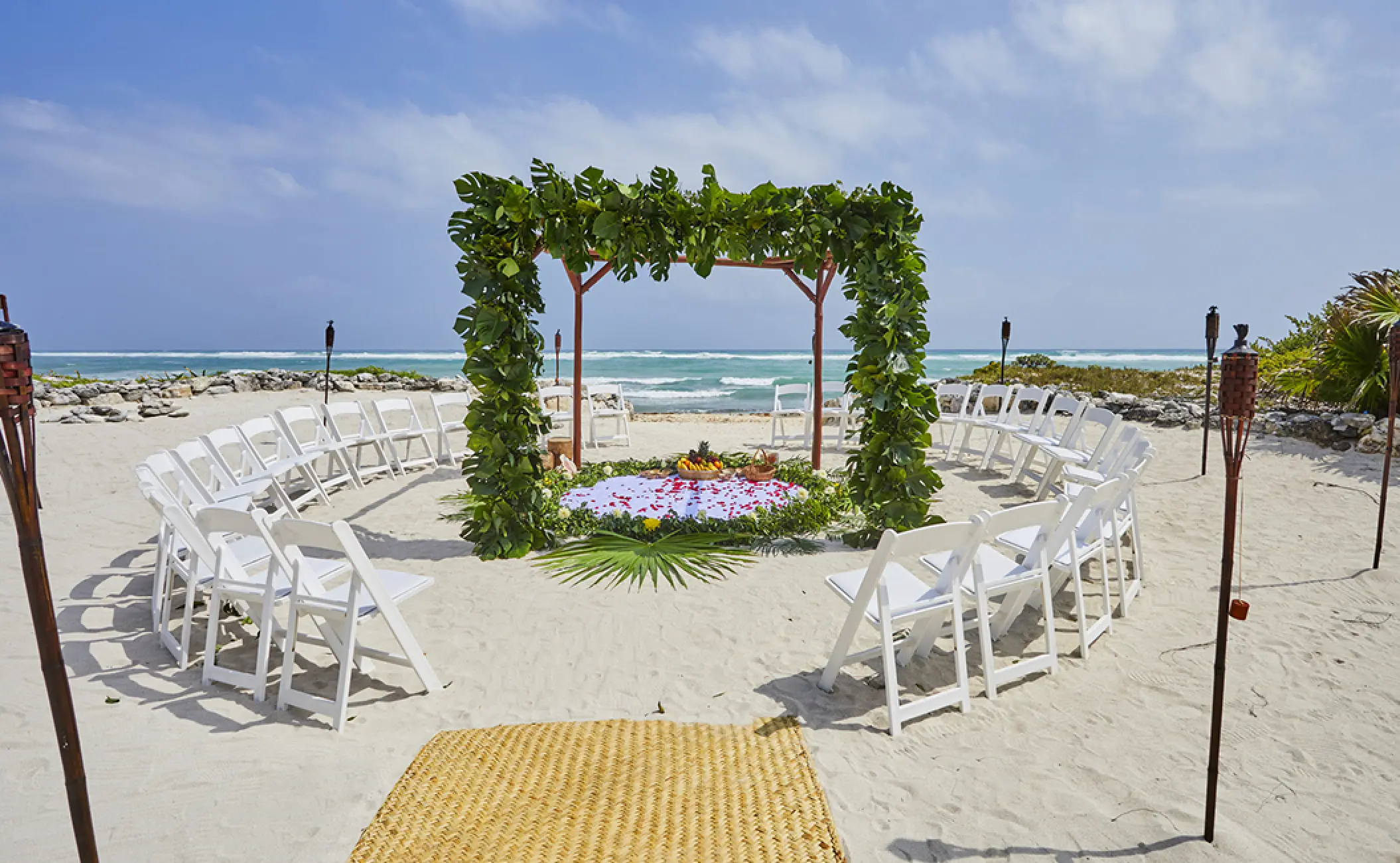 Beachfront wedding ceremony with greenery arch and circular seating at Bahia Principe Luxury Akumal, Tulum