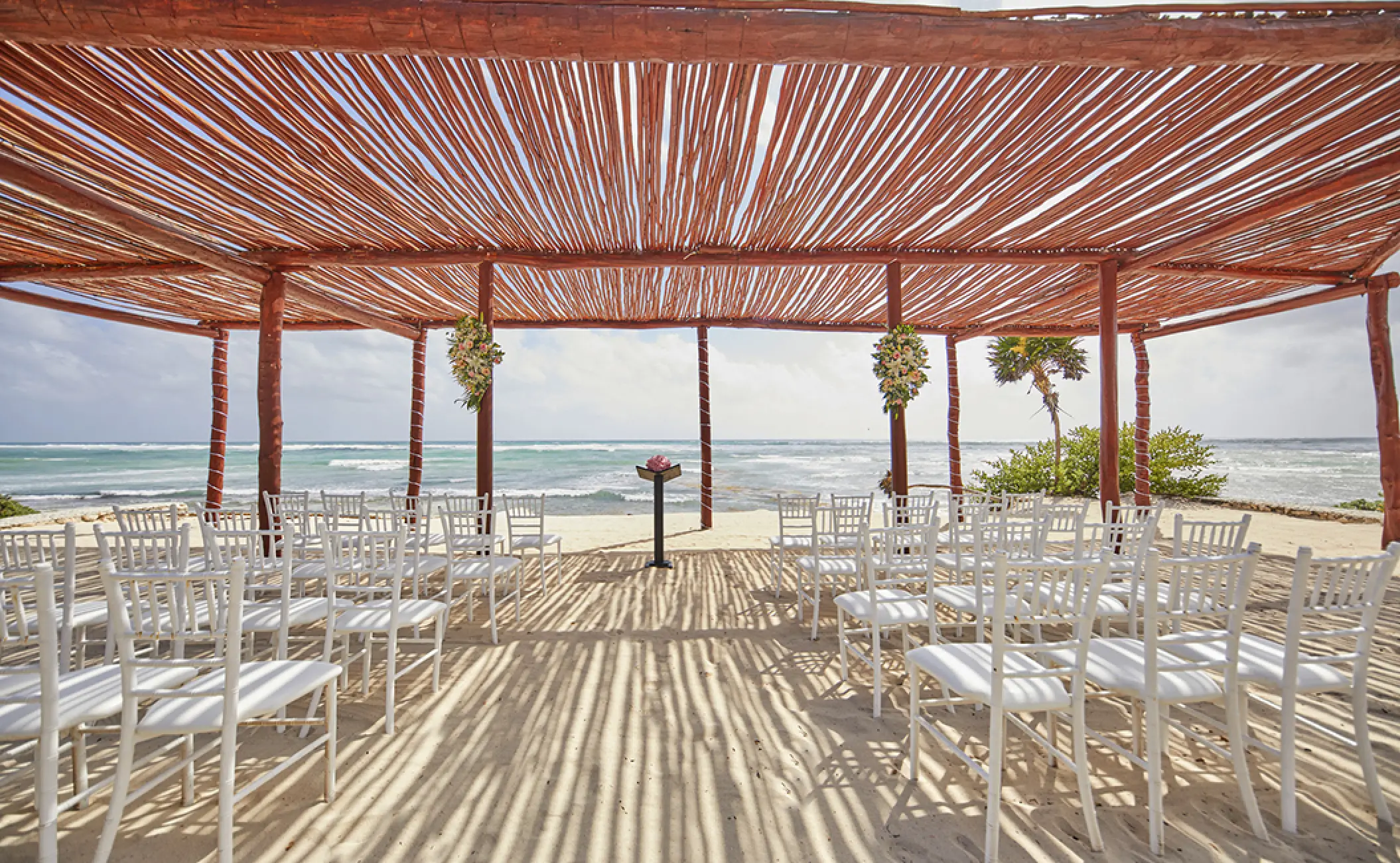 Beachfront wedding ceremony under a wooden pergola at Bahia Principe Luxury Akumal, Tulum