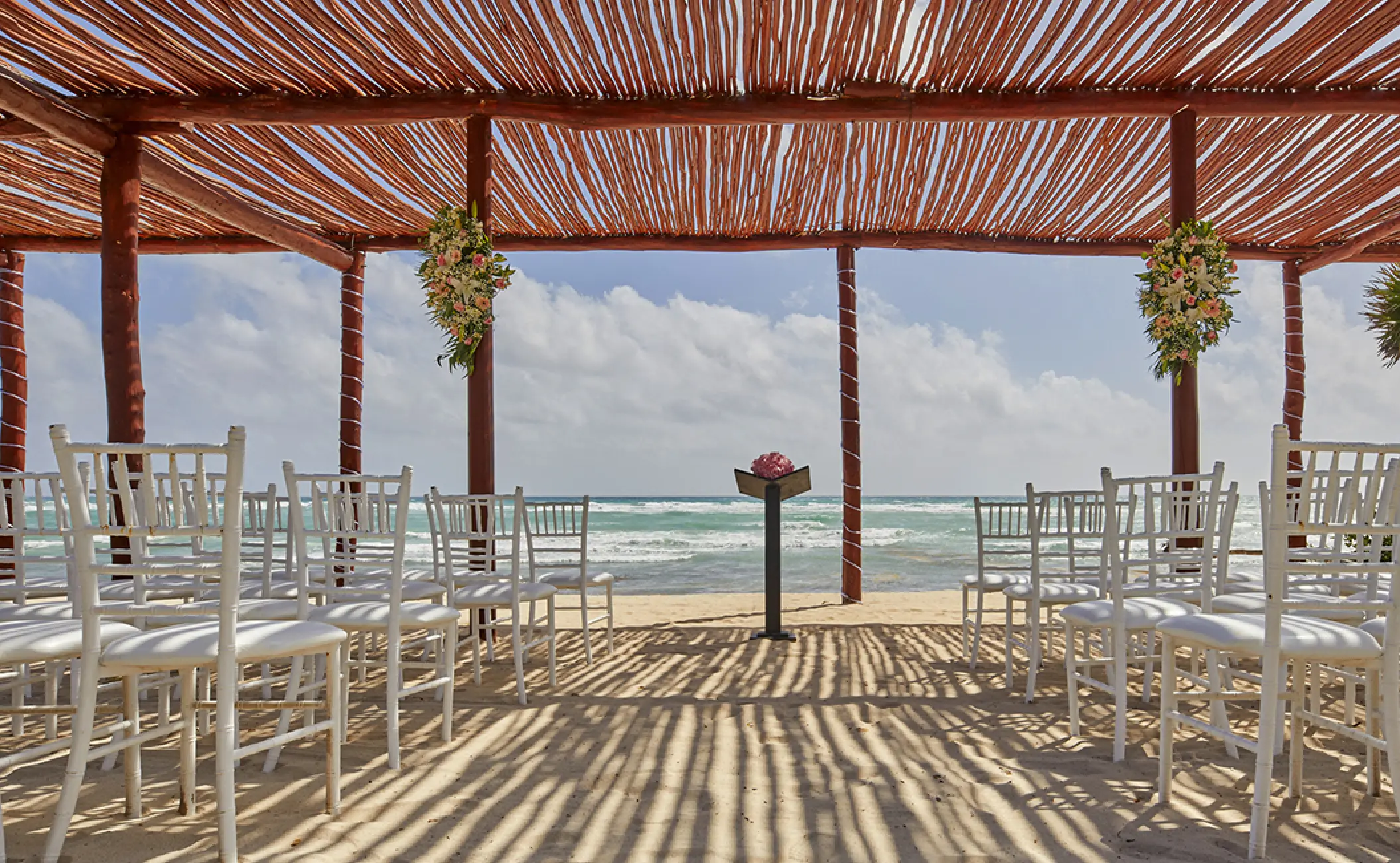 Beachfront wedding ceremony under a wooden pergola at Bahia Principe Luxury Akumal, Tulum