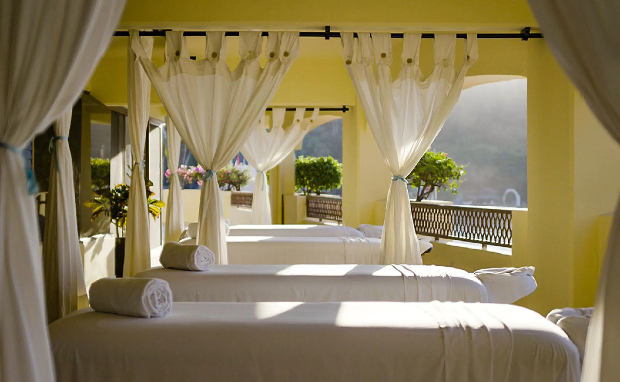 Outdoor spa treatment beds with white linens and draped curtains at Barcelo Puerto Vallarta