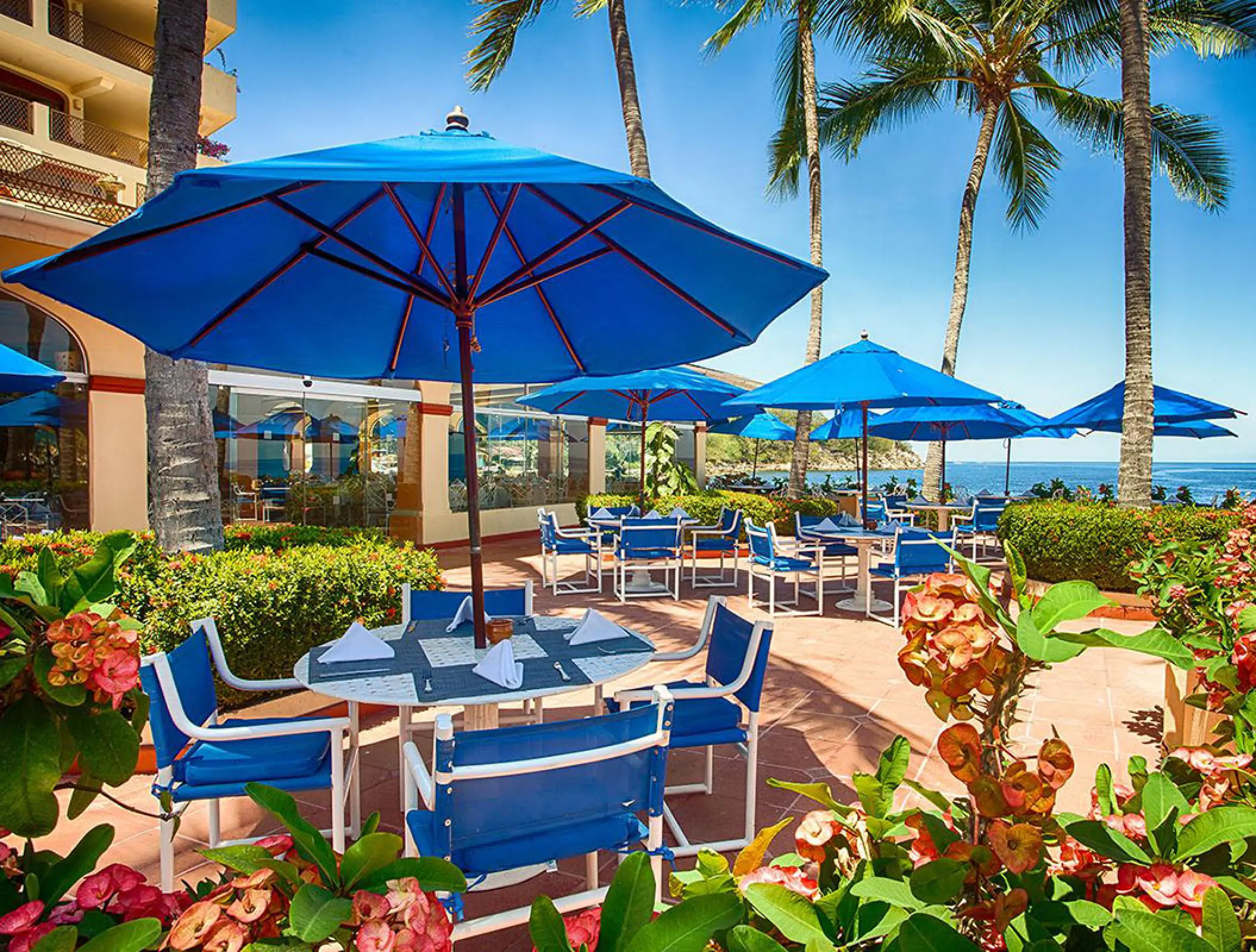 Outdoor dining terrace with blue umbrellas at Barcelo Puerto Vallarta