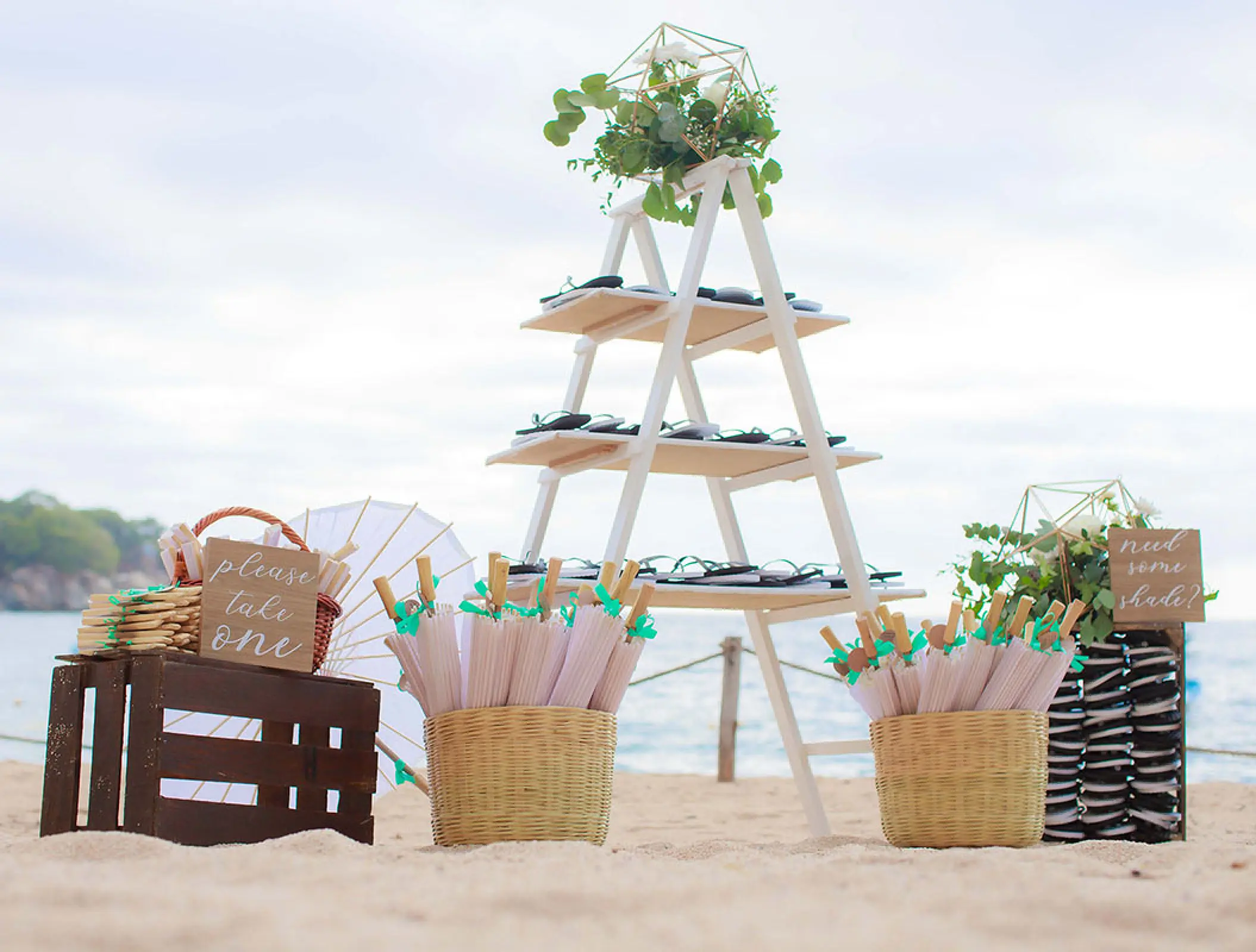 Wedding guest favors station with fans and umbrellas on the beach at Barcelo Puerto Vallarta
