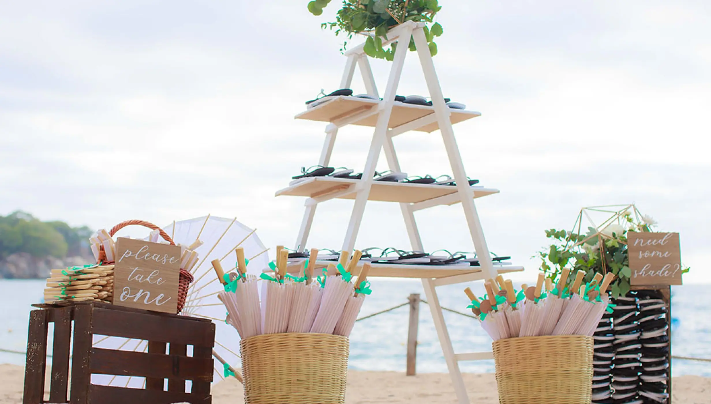 Wedding guest favors station with fans and umbrellas on the beach at Barcelo Puerto Vallarta