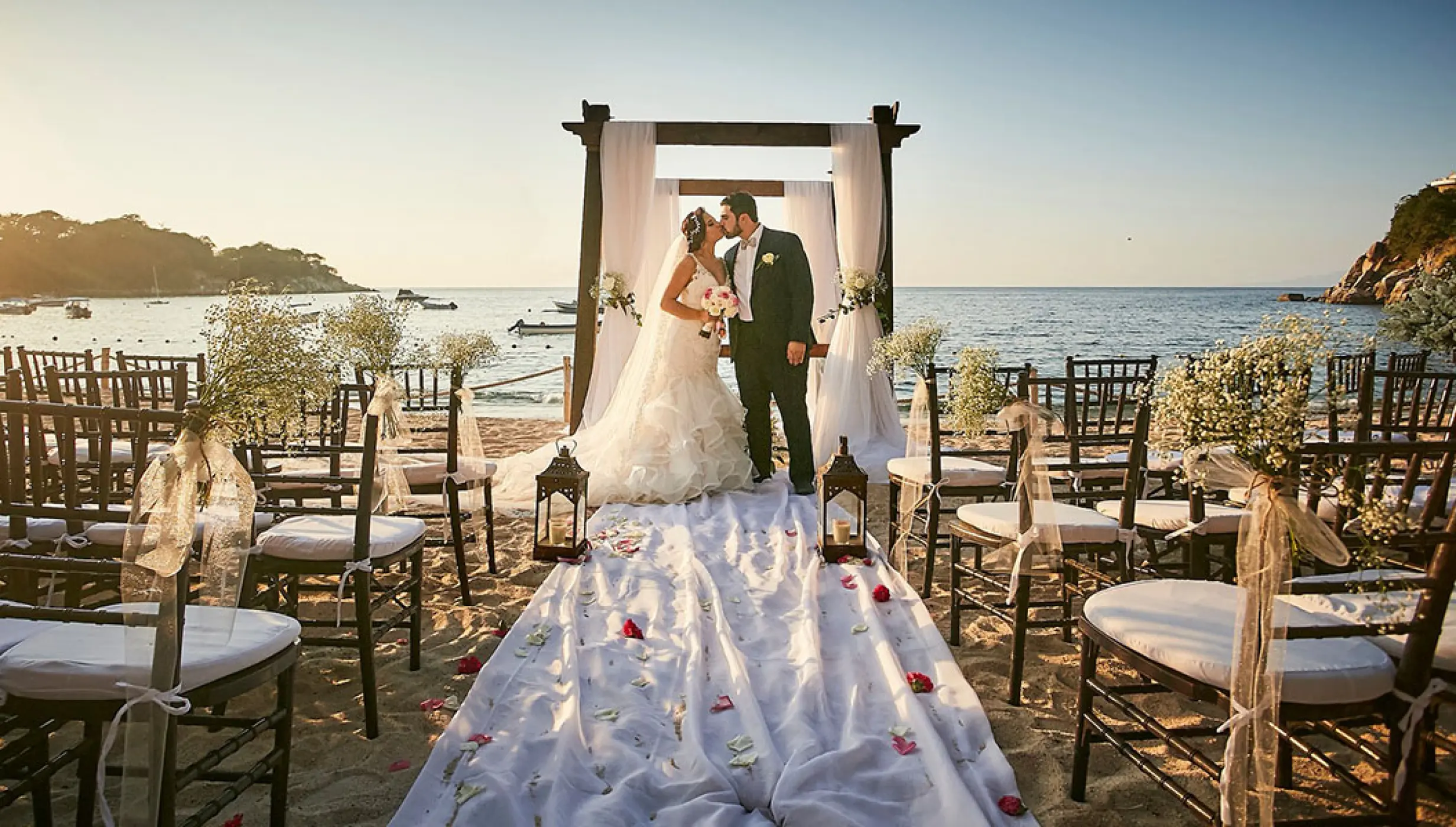 Bride and groom kissing at a beach ceremony at Barcelo Puerto Vallarta