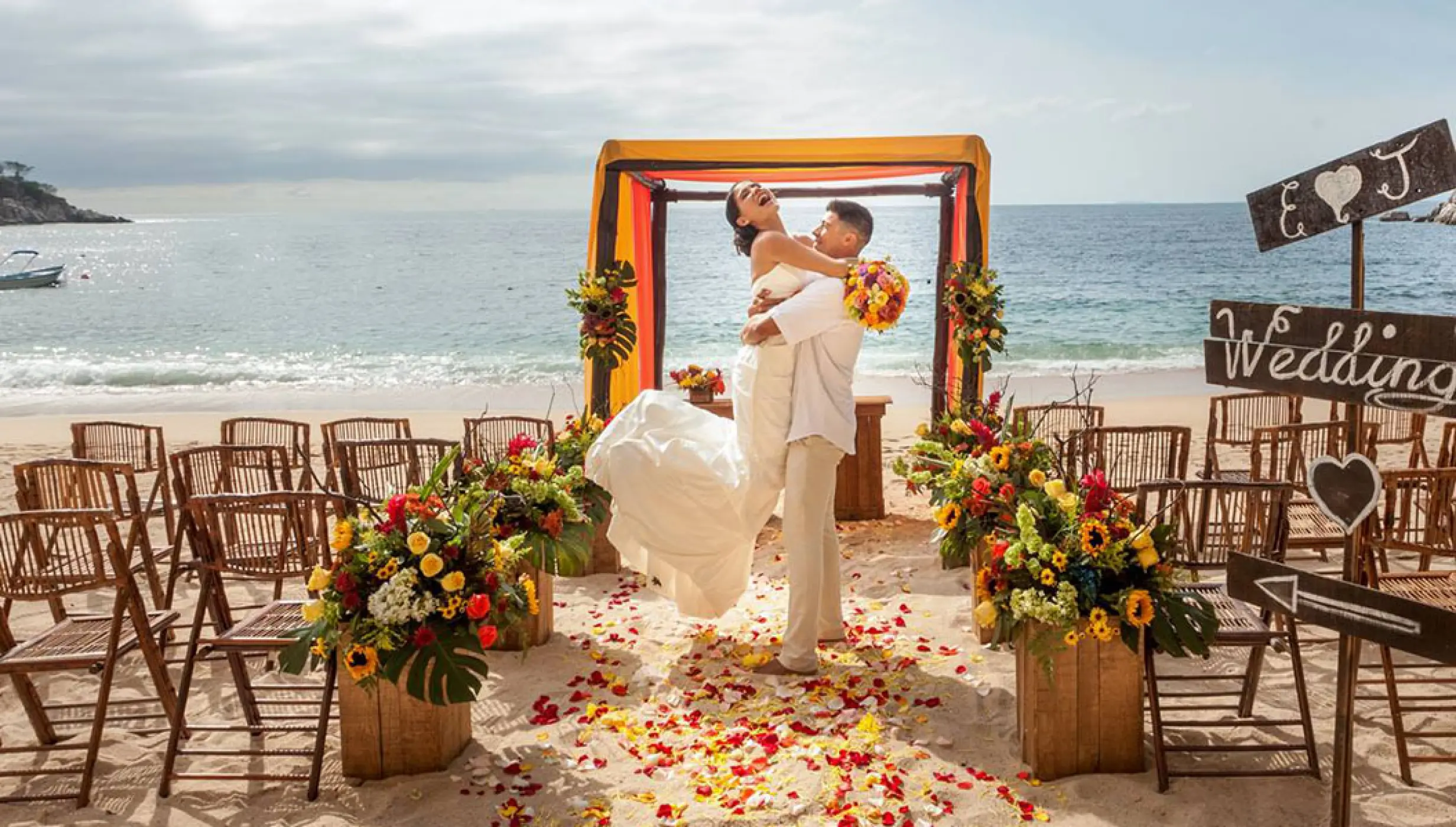 Groom lifting the bride at a beach ceremony setup at Barcelo Puerto Vallarta