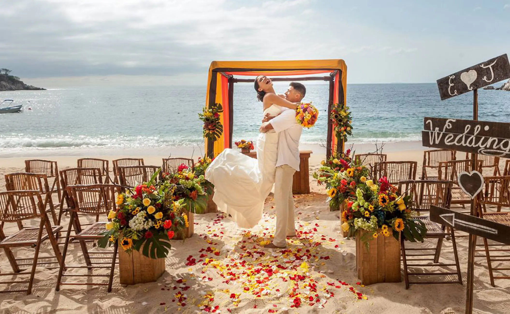 Groom lifting the bride at a beach ceremony setup at Barcelo Puerto Vallarta