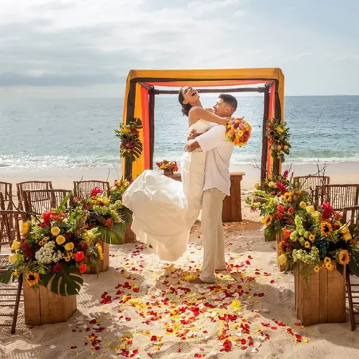 Groom lifting the bride at a beach ceremony setup at Barcelo Puerto Vallarta