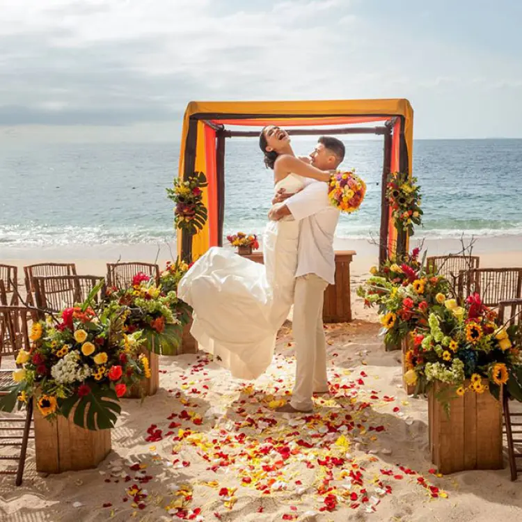 Groom lifting the bride at a beach ceremony setup at Barcelo Puerto Vallarta