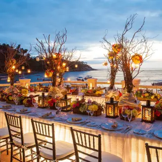 Outdoor wedding reception at Barcelo Puerto Vallarta with lanterns and floral decor overlooking the bay at sunset