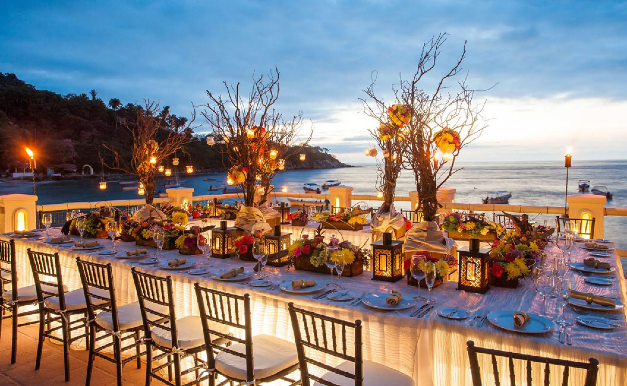 Outdoor wedding reception at Barcelo Puerto Vallarta with lanterns and floral decor overlooking the bay at sunset