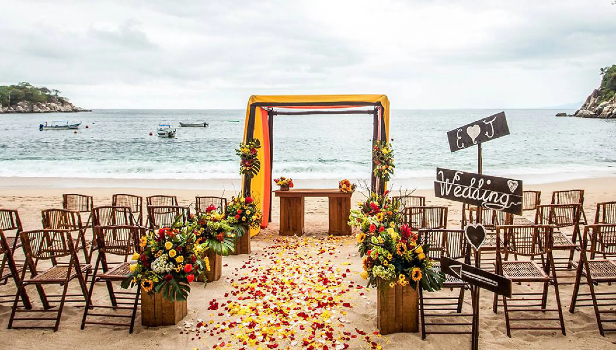 Beach wedding ceremony with floral aisle and wooden chairs at Barcelo Puerto Vallarta