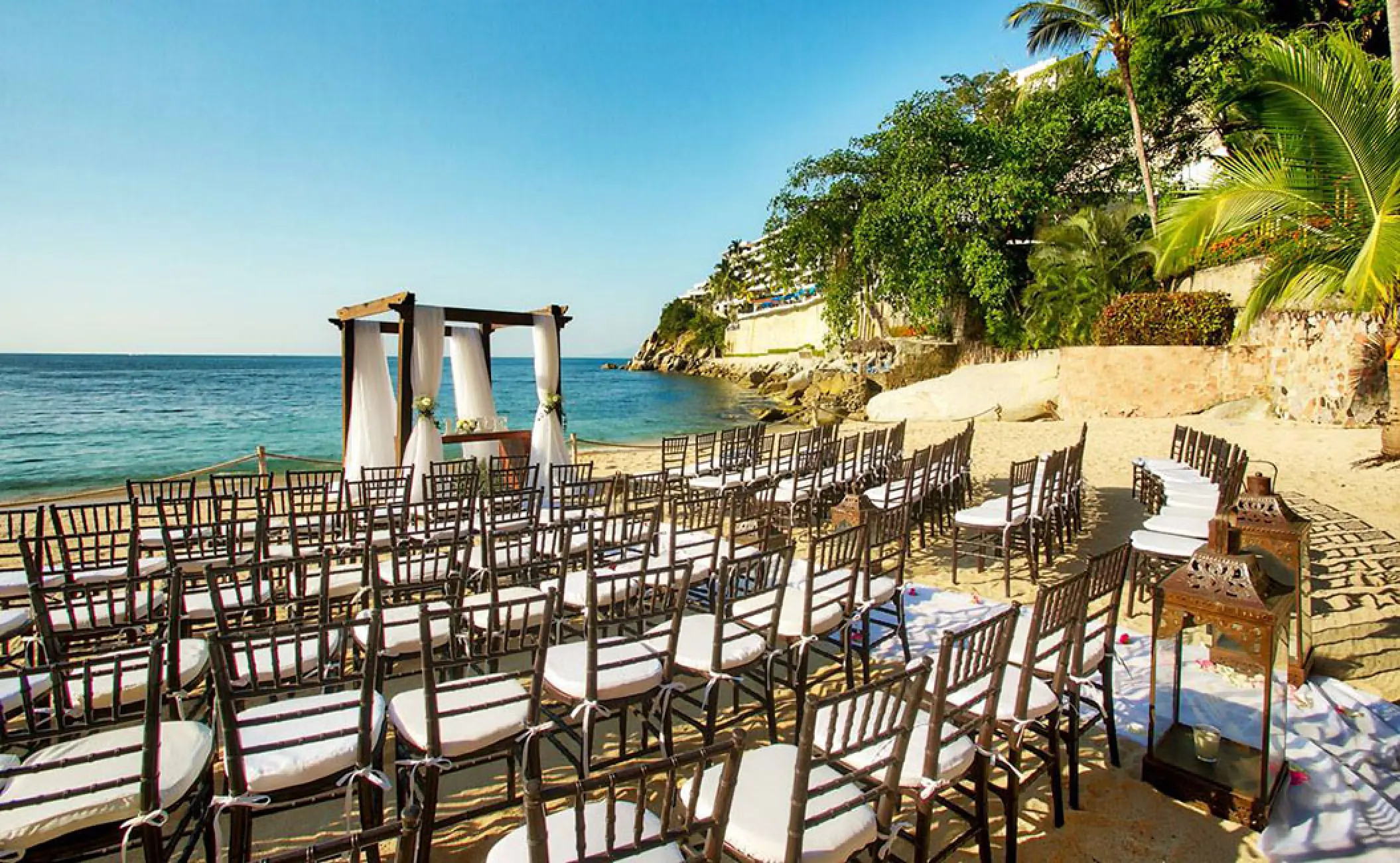 Beachfront wedding ceremony setup with a wooden gazebo and chairs at Barcelo Puerto Vallarta