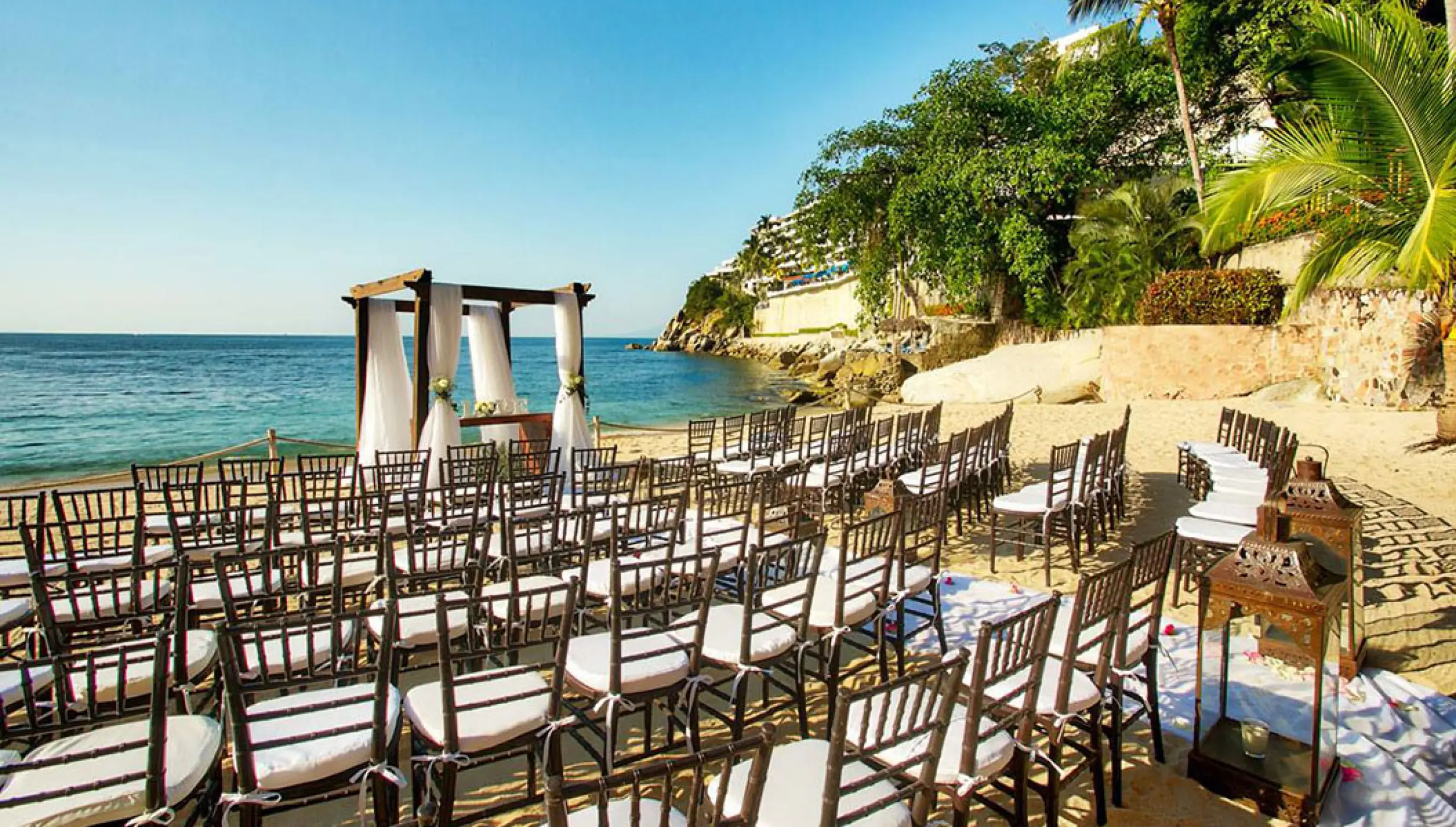 Beachfront wedding ceremony setup with a wooden gazebo and chairs at Barcelo Puerto Vallarta