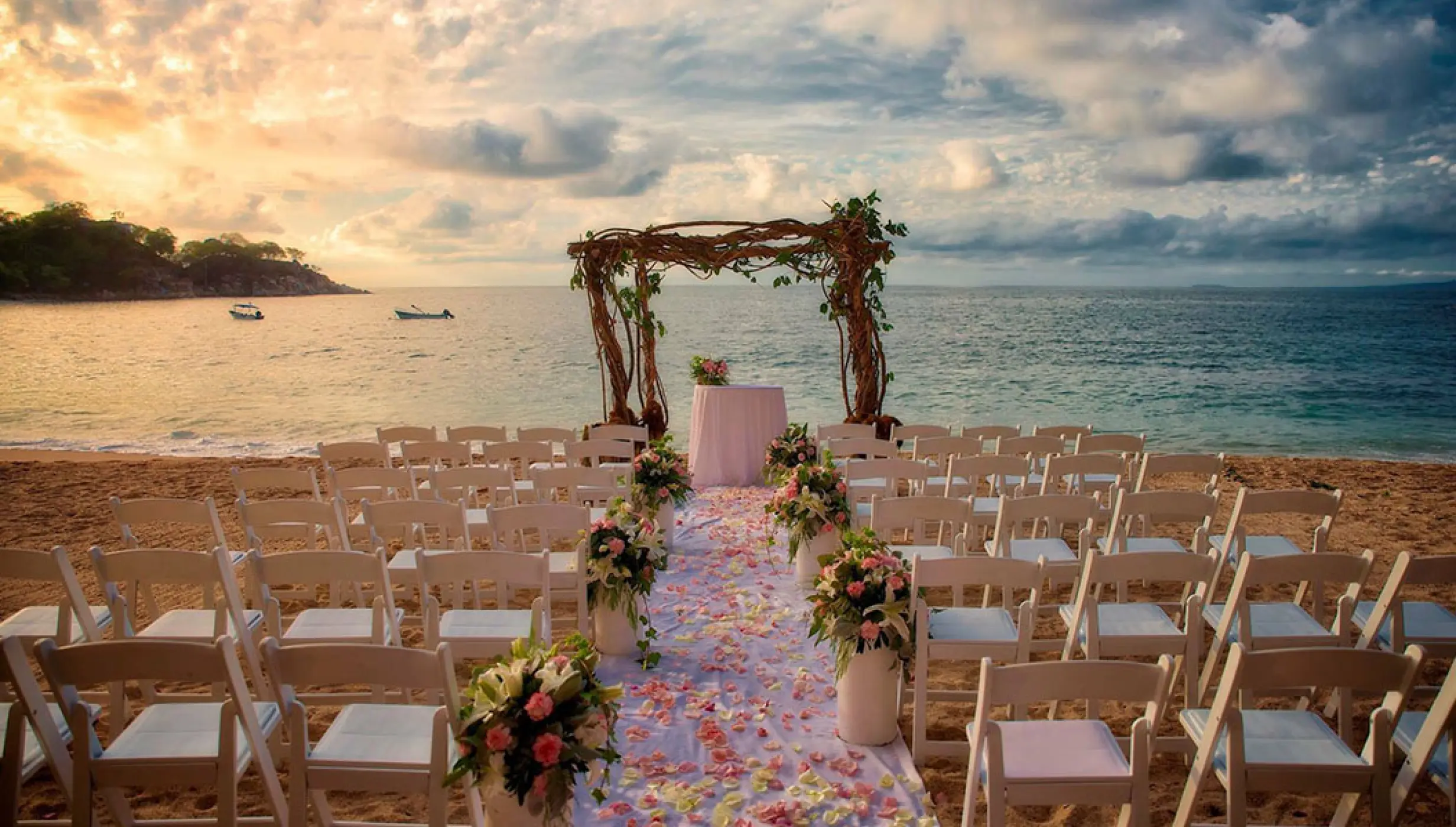 Beachfront wedding ceremony with a floral arch and white chairs at Barcelo Puerto Vallarta