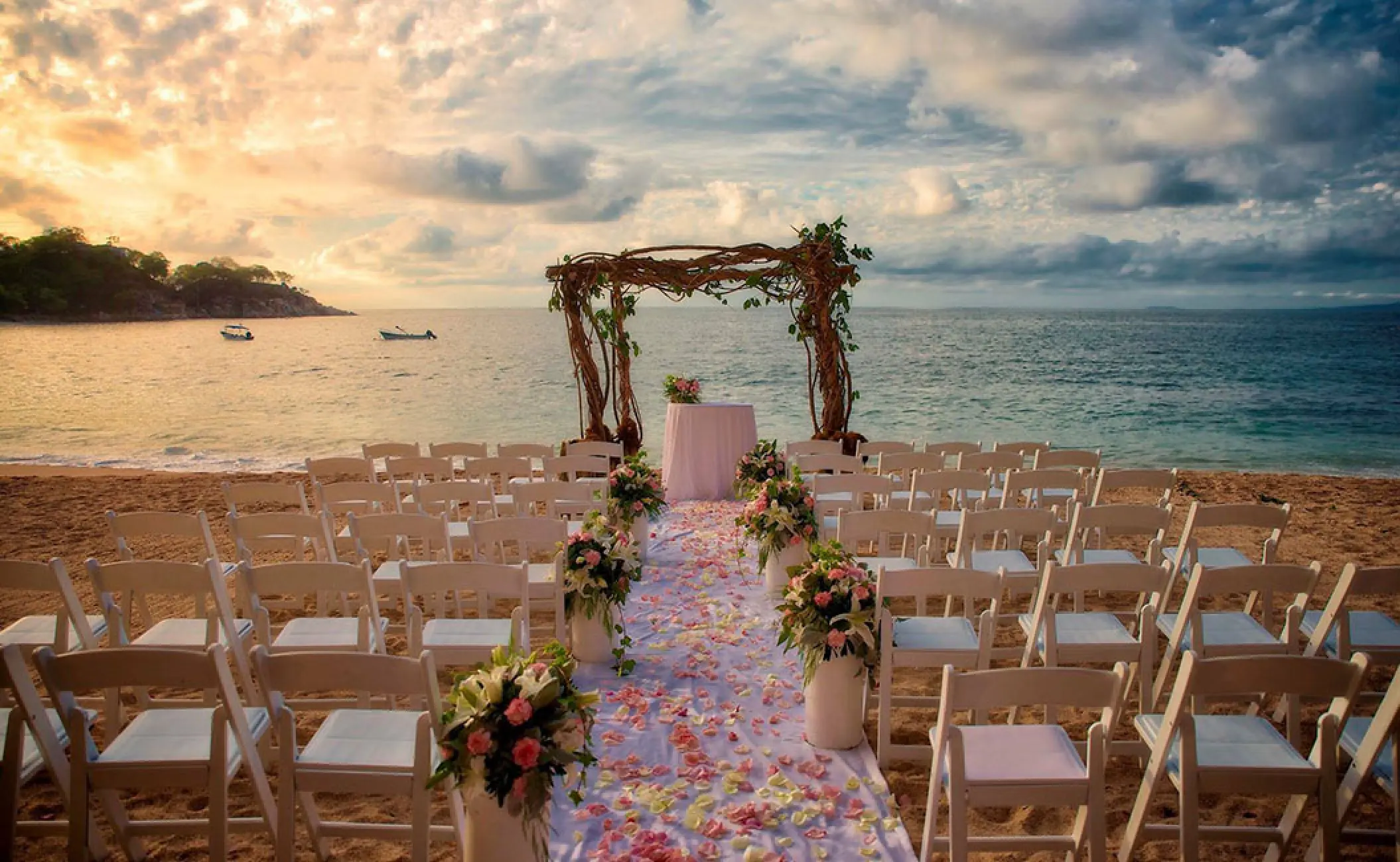Beachfront wedding ceremony with a floral arch and white chairs at Barcelo Puerto Vallarta